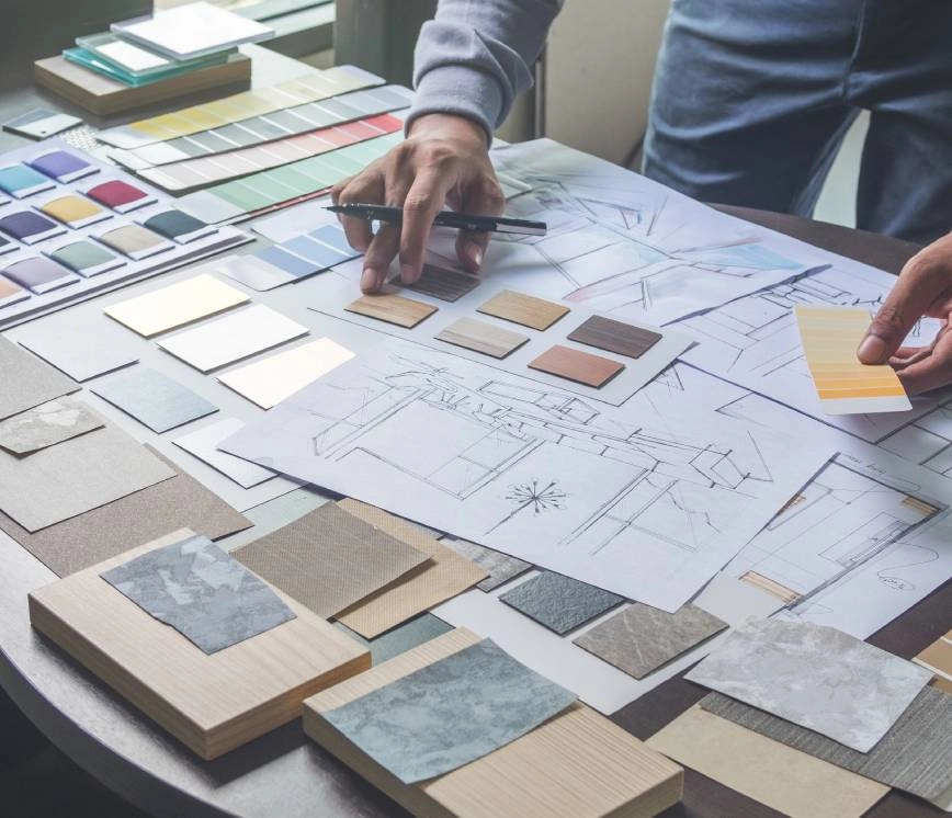 Interior design specialist standing over a table looking at designs and color samples.