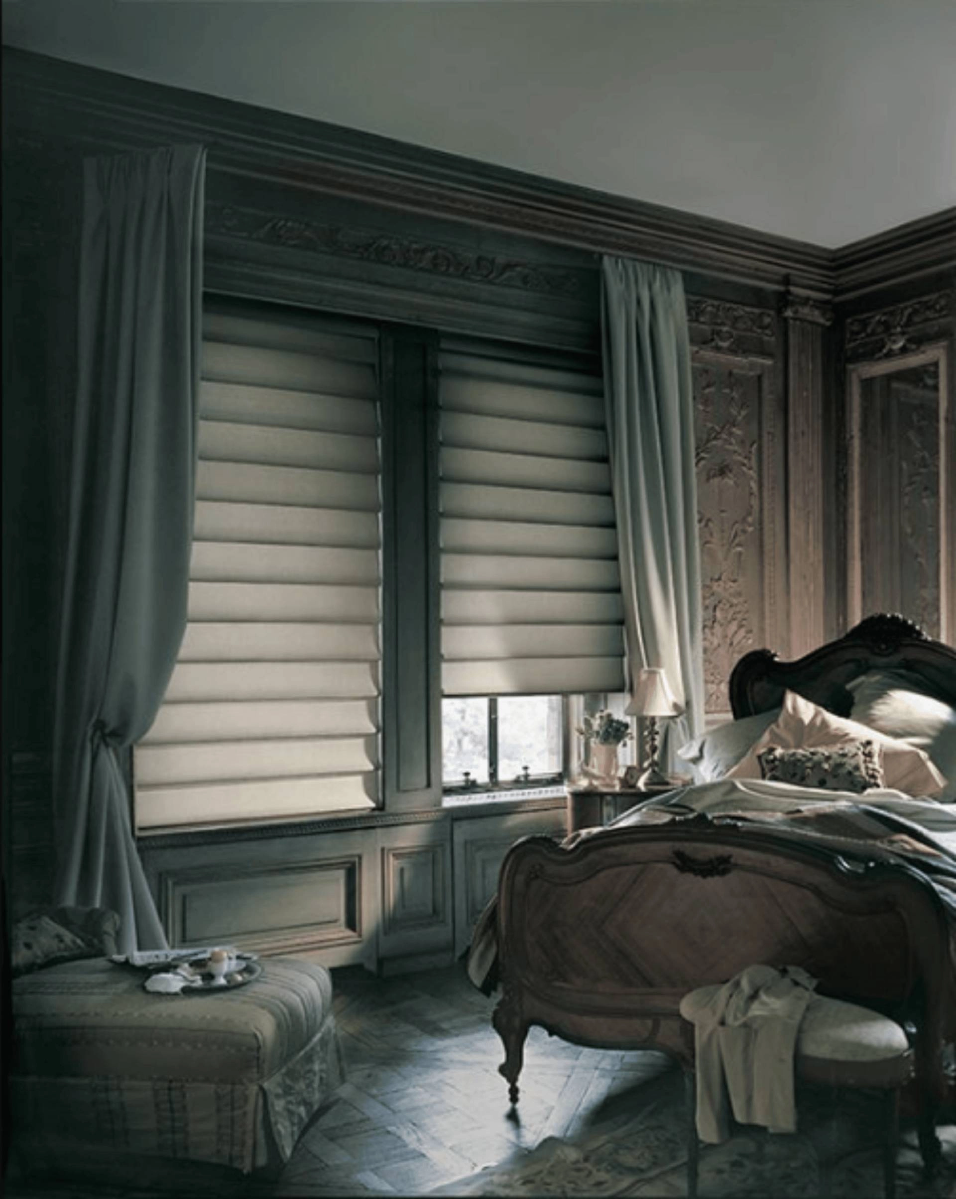 Vignette® Roman shades layered with drapery panels in a traditional bedroom.