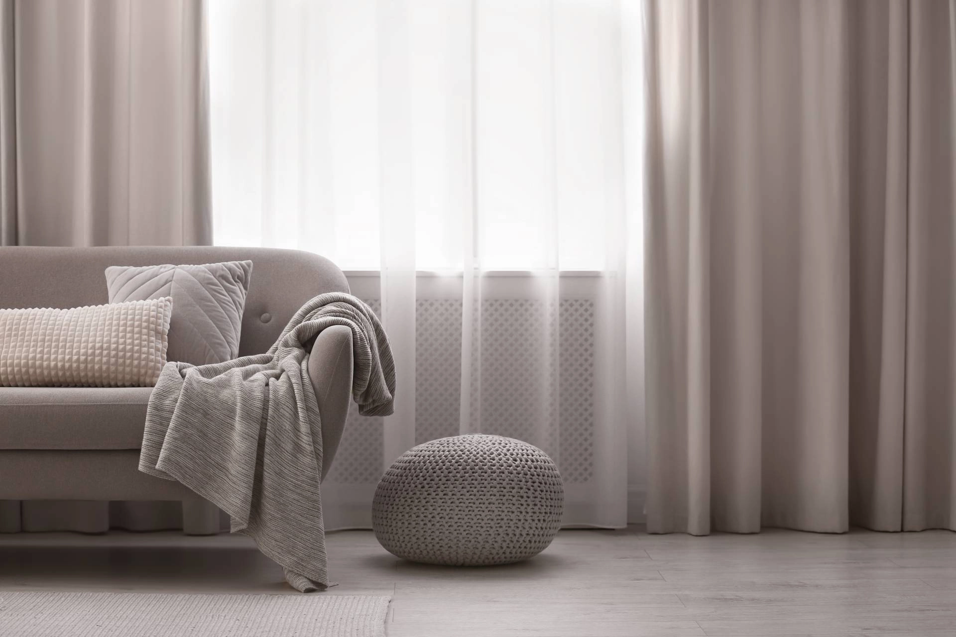 Custom drapery covering a window beside a sofa and plush ottoman near Tucson, AZ