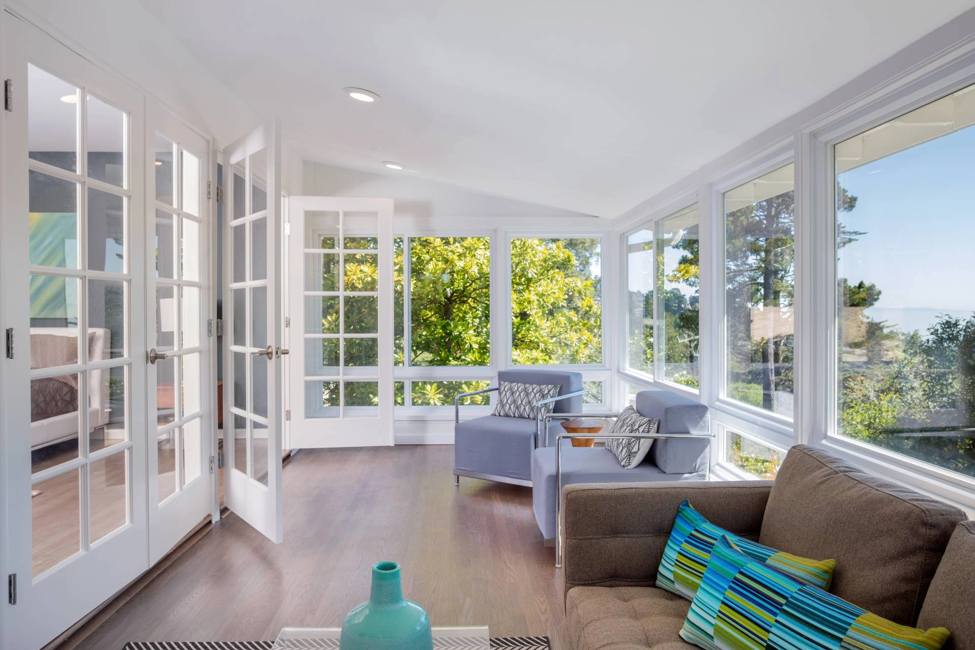 Sunroom with multiple accent chairs and window shades covering sunroom windows