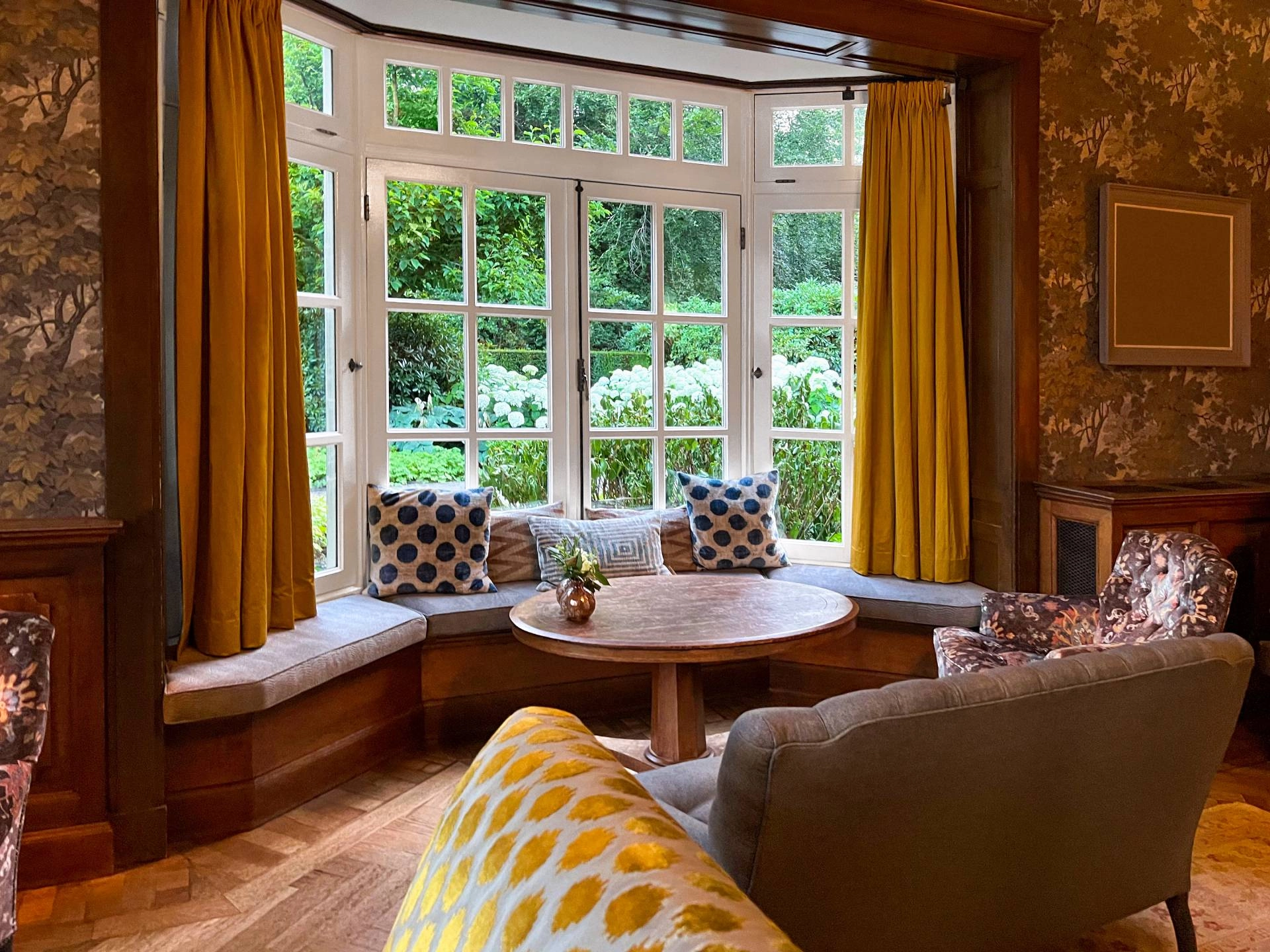 A cozy nook with layered window treatments for the bay windows in a moody space