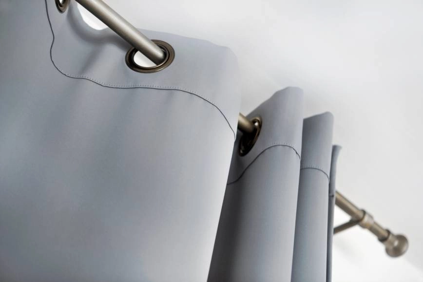 Silver drapery rod holding gray drapery.