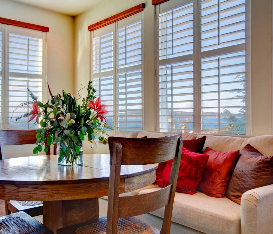 Quaint dining nook with round wooden table and white fabric sofa.