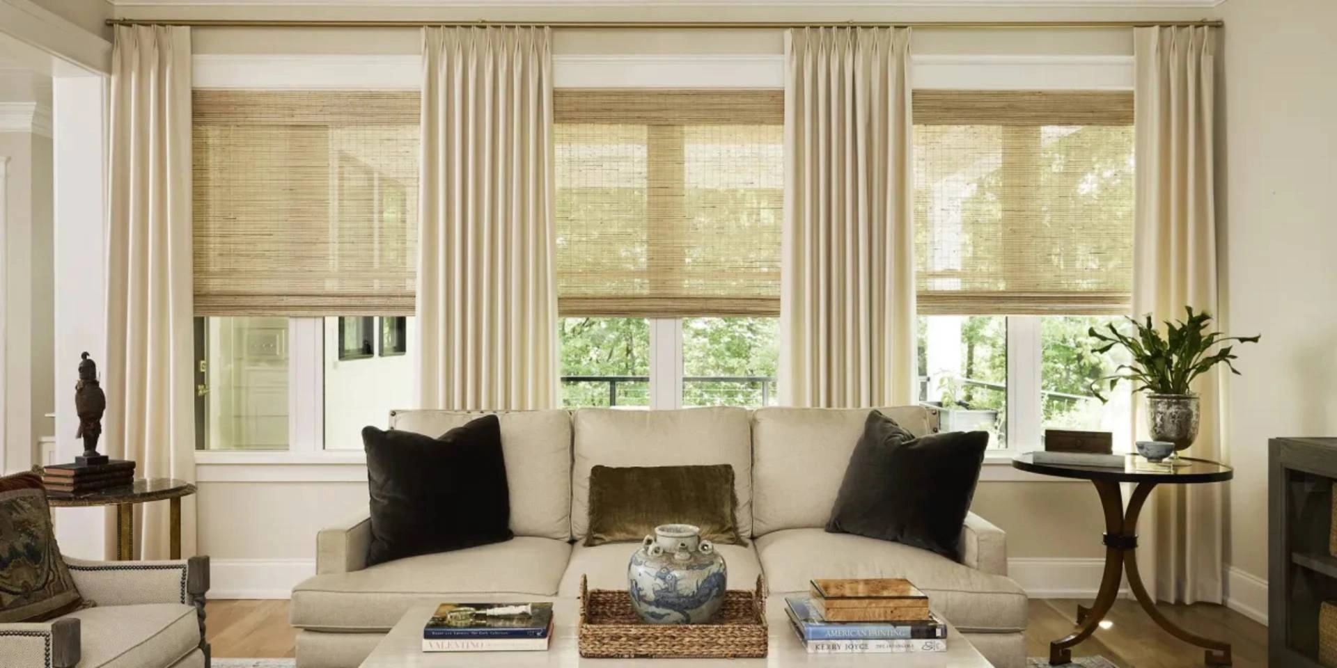 Chic, custom Carole™ Fabrics drapes on three living room windows, layered with woven shades