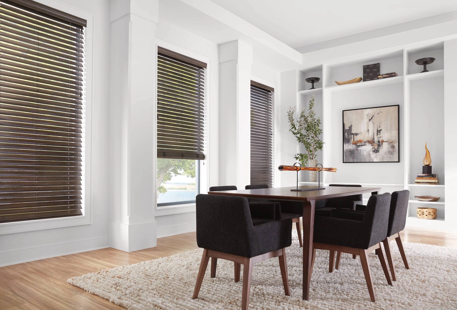 Hunter Douglas wood blinds covering three windows in a posh dining room.