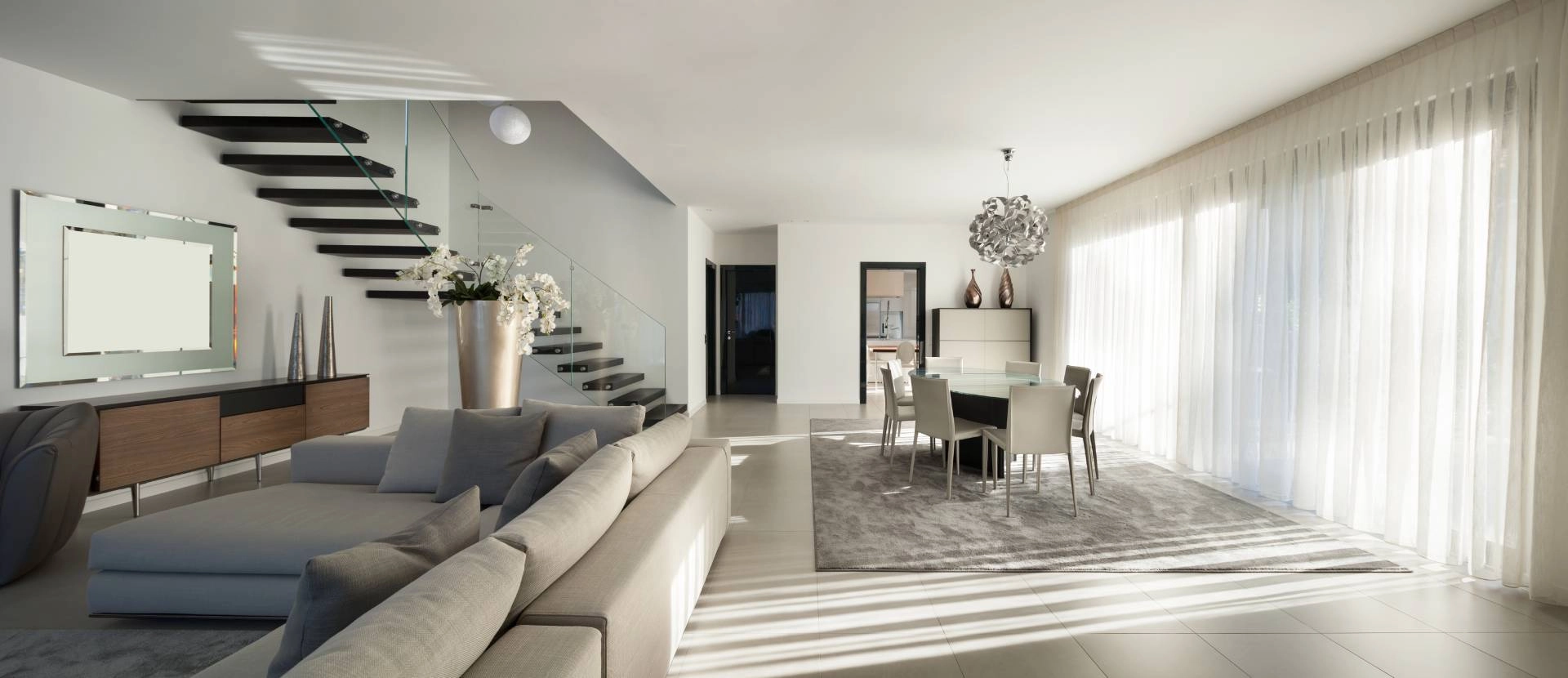 A chic and modern home with sleek details, including vertical sheer shades on large windows
