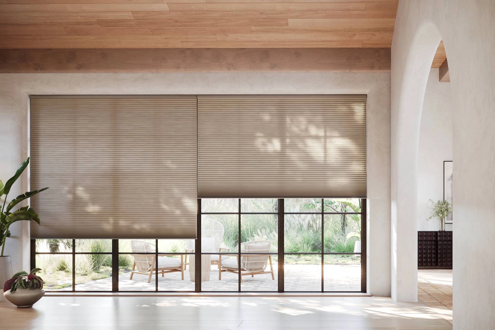 Energy-efficient cellular shades filter sunlight in a living room opening to a patio.