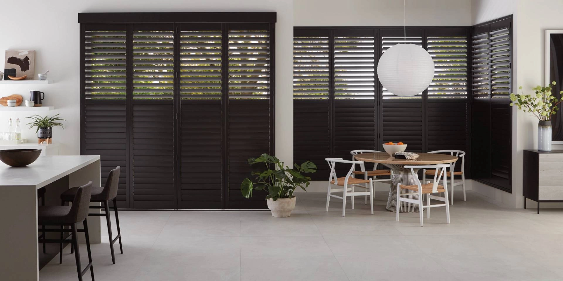 Black Hunter Douglas wood shutters as large window treatments for a Texas home’s spacious kitchen