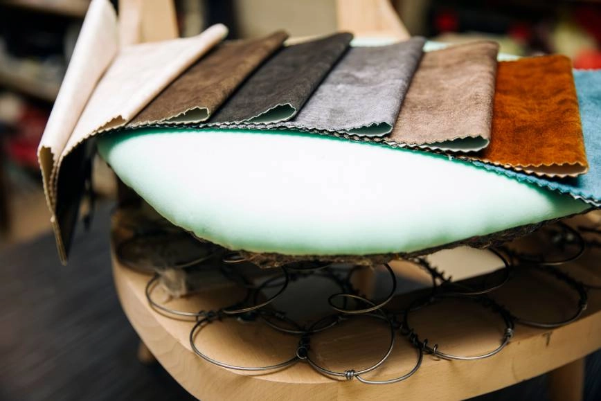 Image of an accent chair undergoing a custom upholstery service with various fabric choices on top