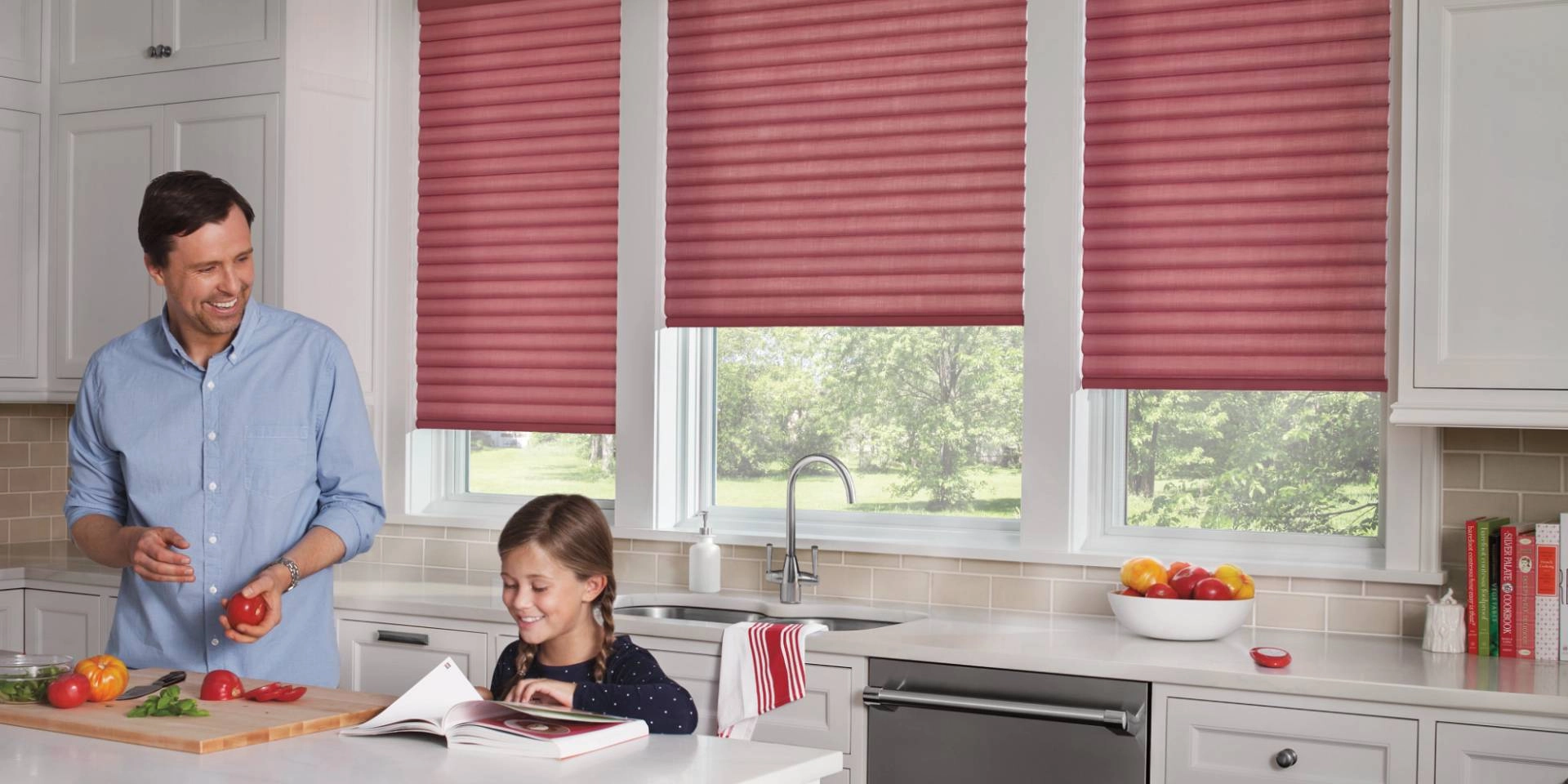 Red Hunter Douglas Sonnette® Roller Shades on a kitchen window near a father and daughter