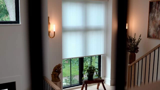 A window in a staircase with Hunter Douglas shades.