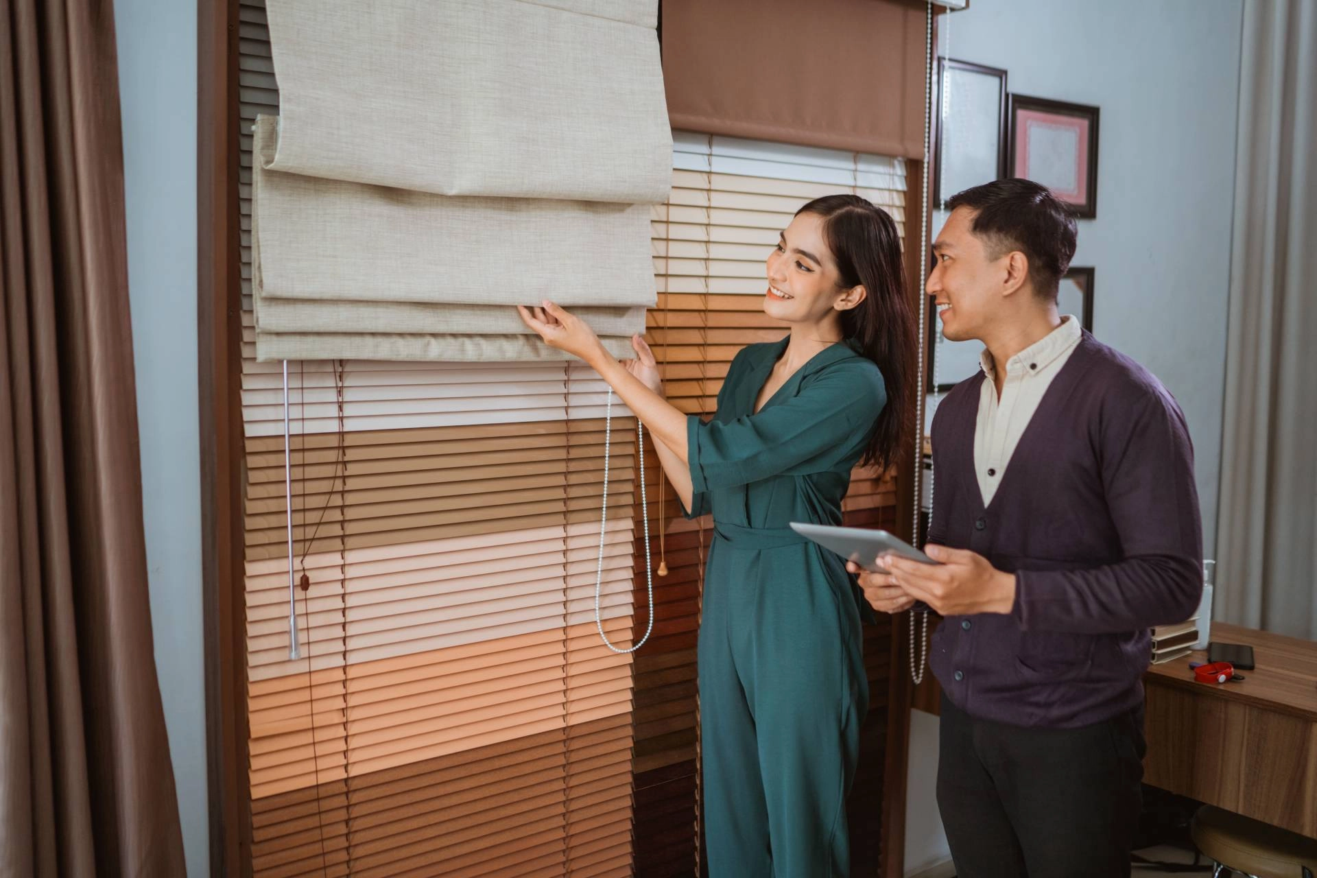 Window treatment professional showing a customer a display with blinds and shades.