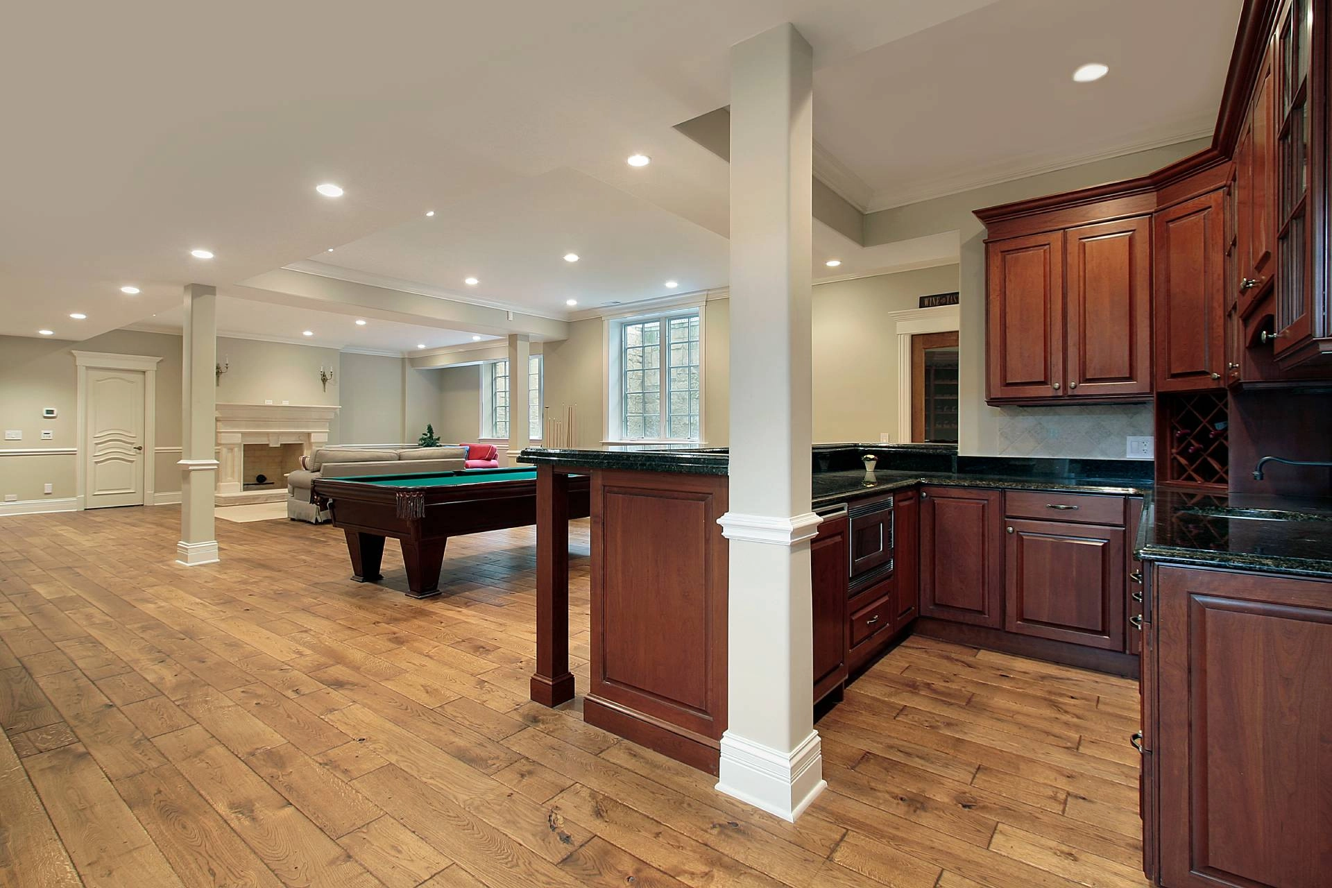 Basement with fireplace, pool table, a home bar/kitchen combination, and windows in need of covering near Concord, MA