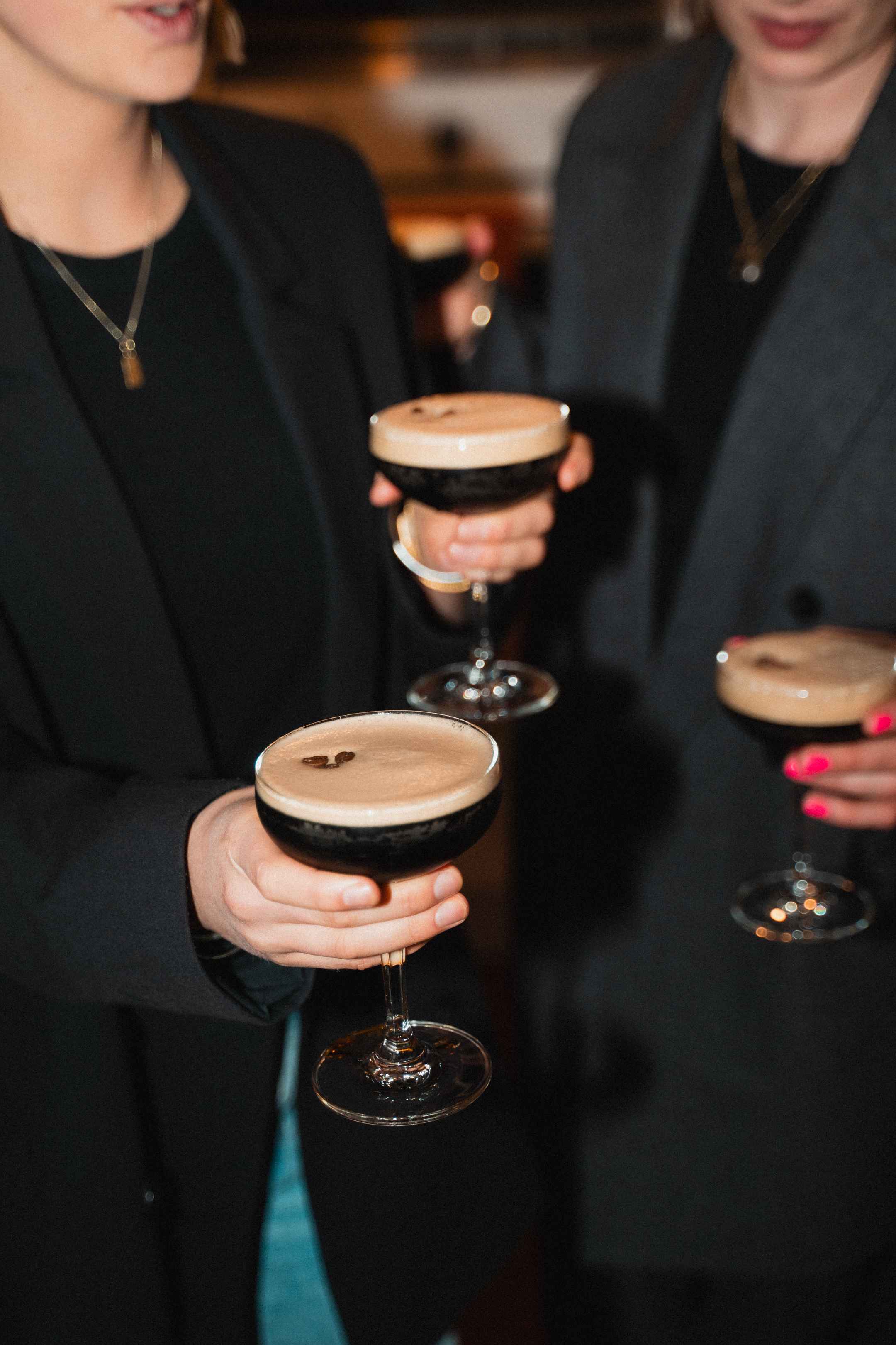 Three people holding Batched Espresso Martini's served in glasses