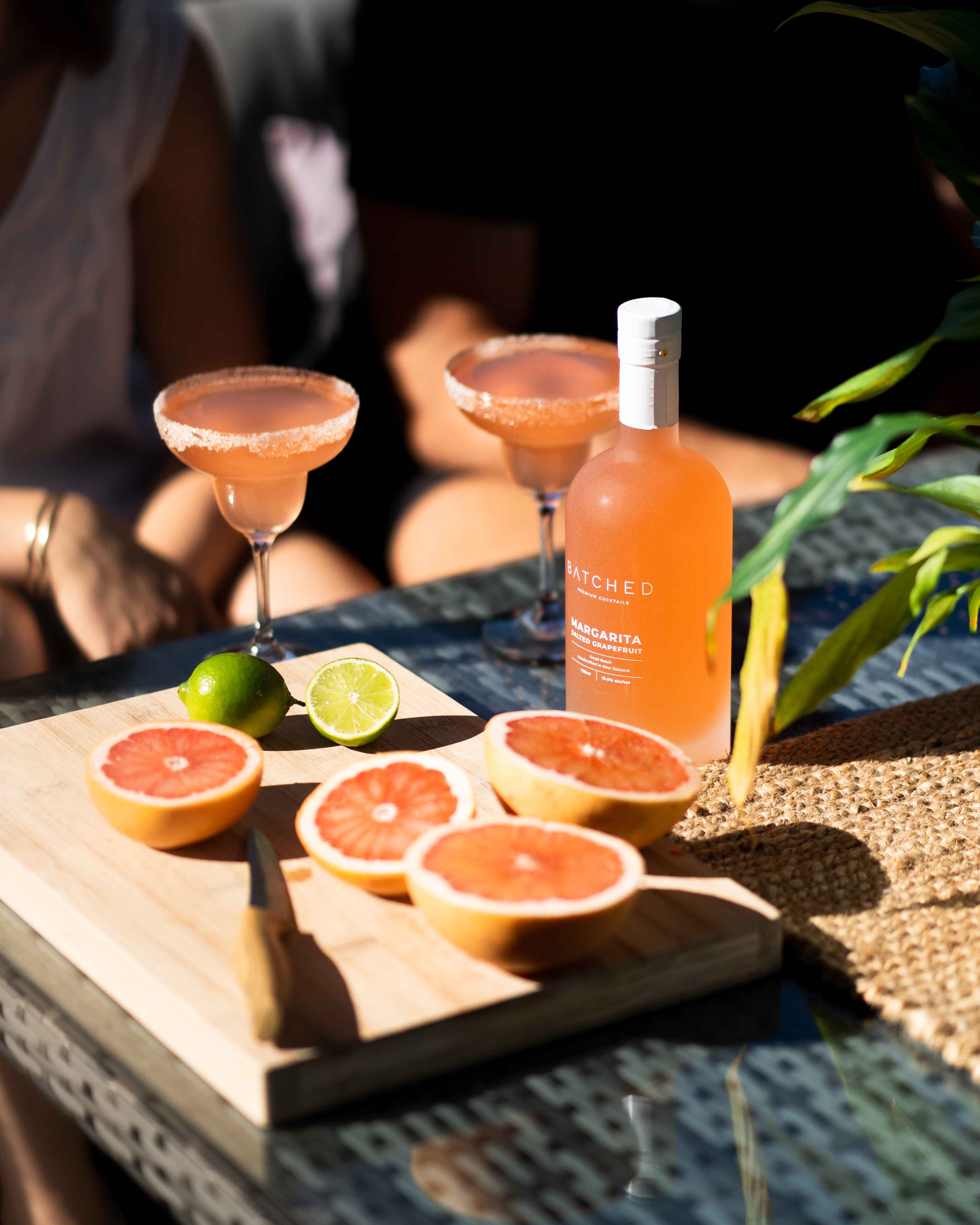 Batched Salted Margarita with bottle chopping board with sliced blood oranges and lime