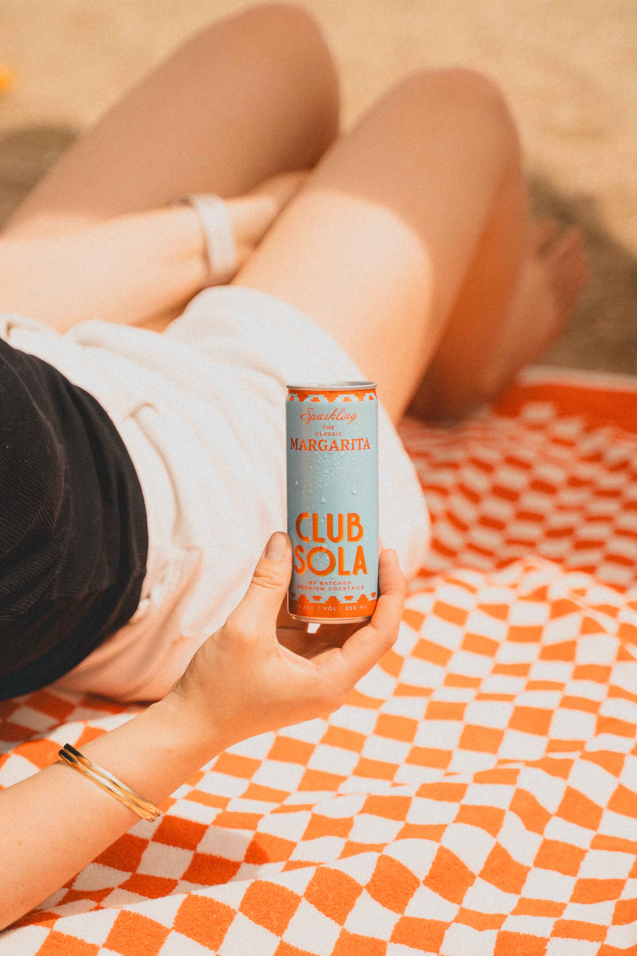 Hand holding can of Club Sola on a towel