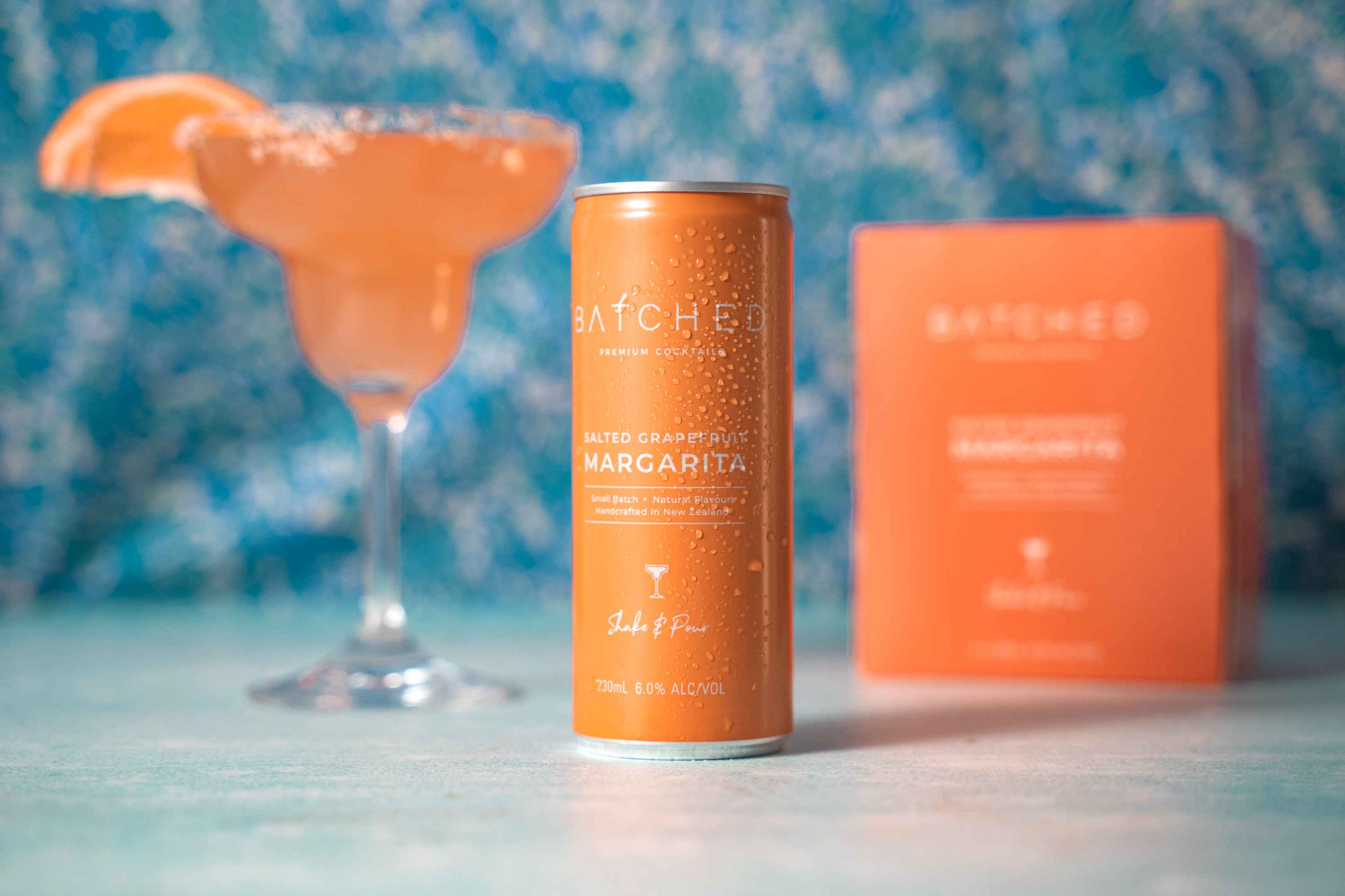 Batched Salted Grapefruit Margarita can on table with box and martini glass in background