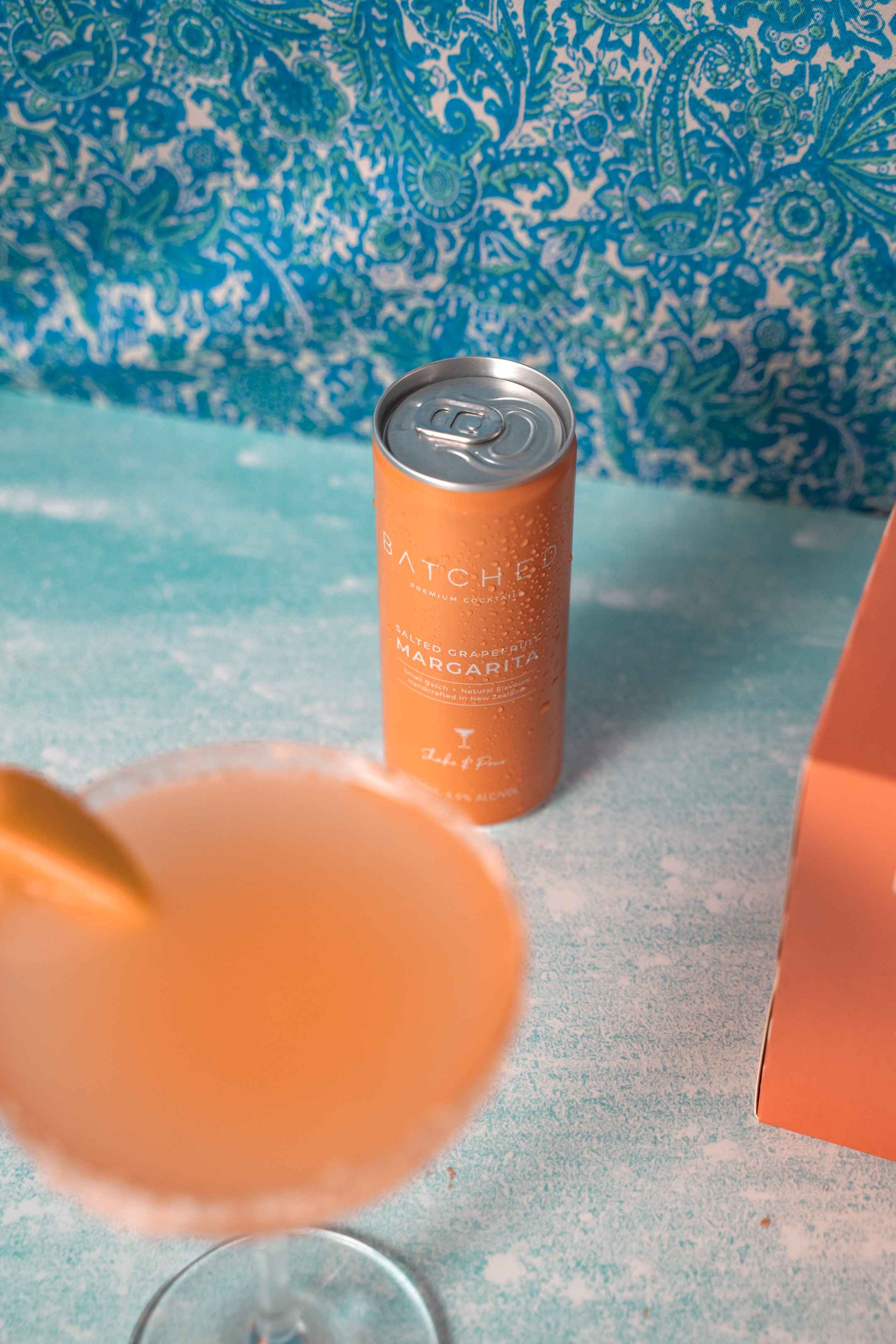 Batched Salted Grapefruit Margarita can on table with a blue background