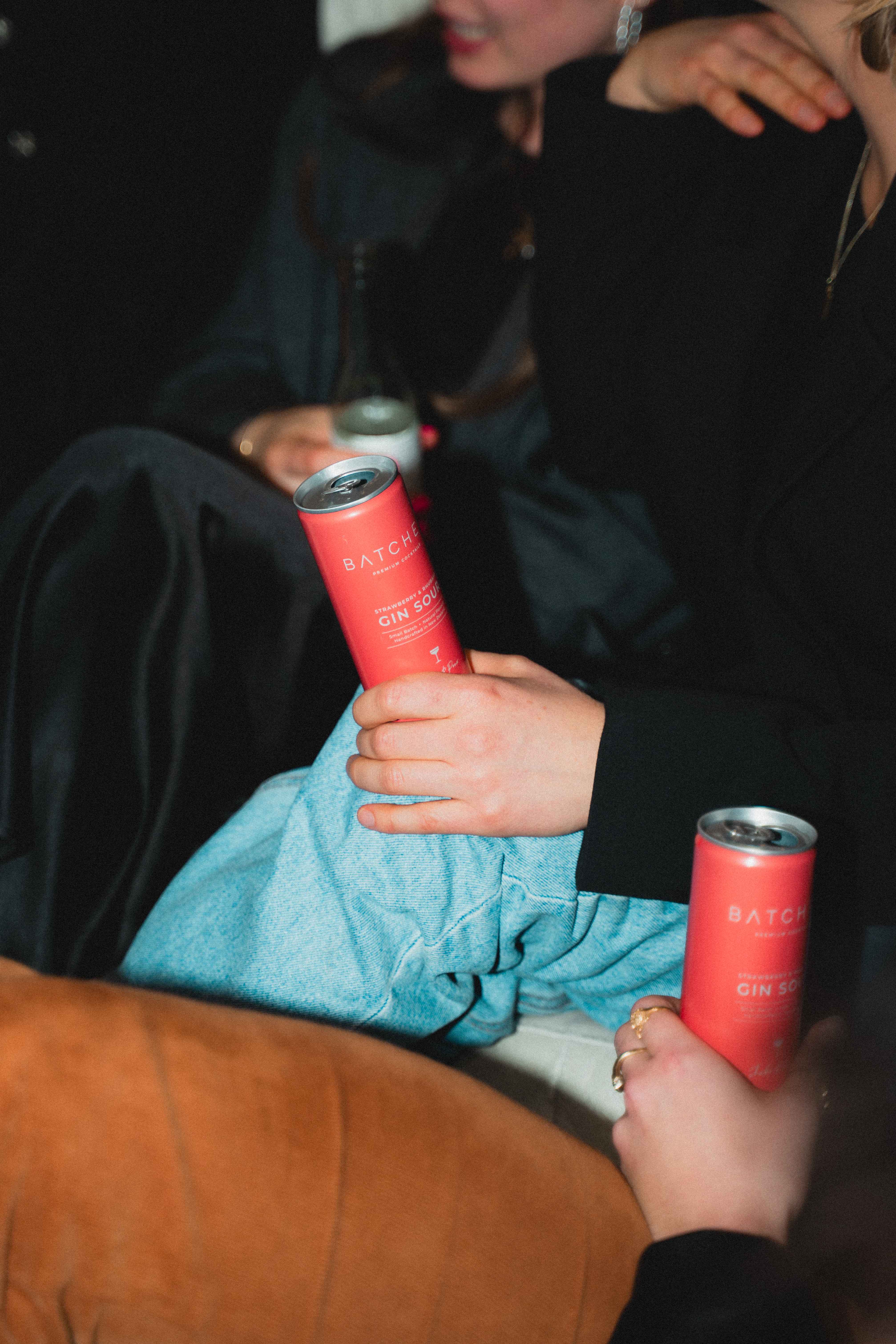 Two people holding Batched Gin Sour drink cans