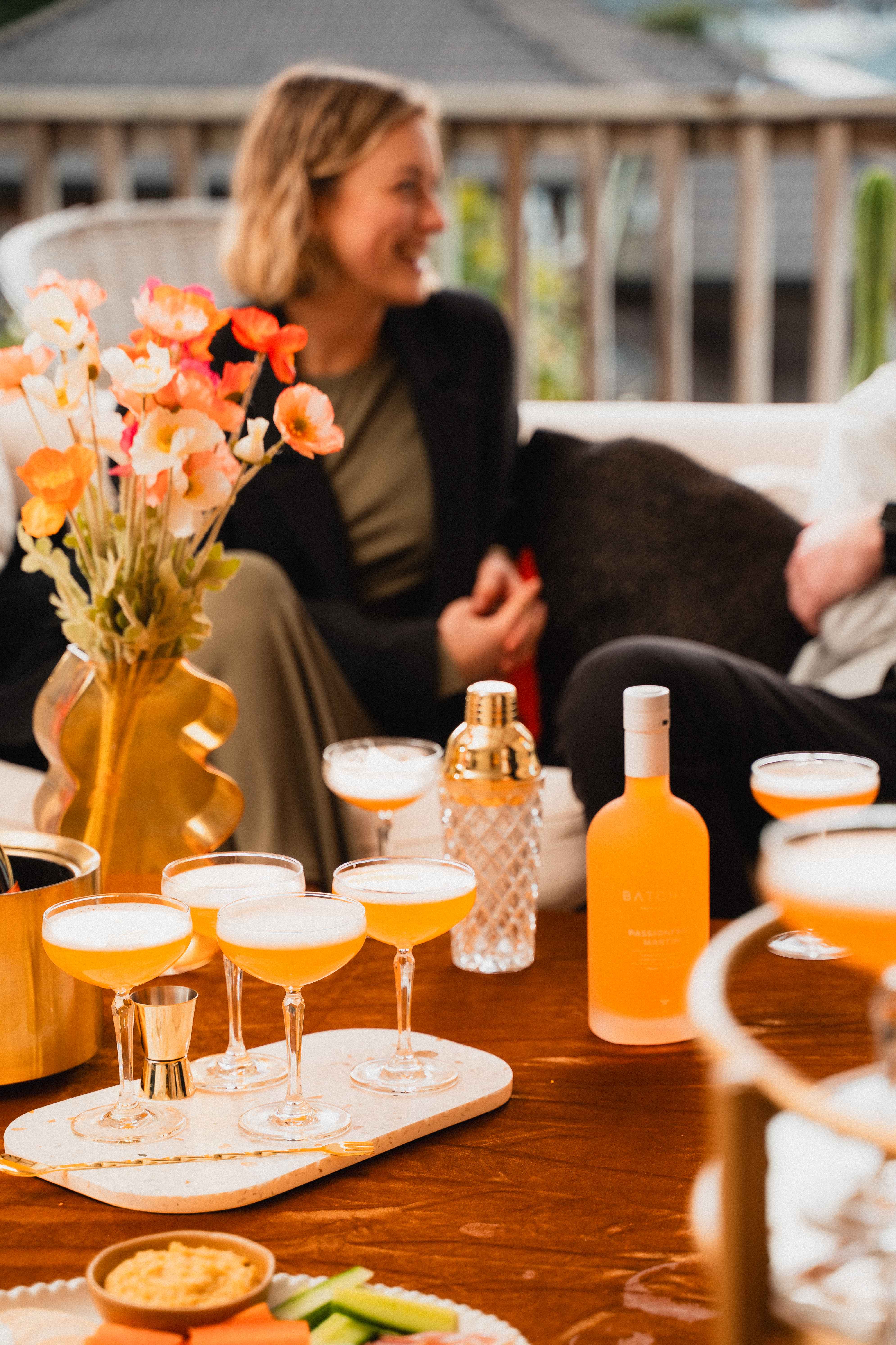 Batched Passionfruit Martini served in martini glasses on a table, with people surrounding