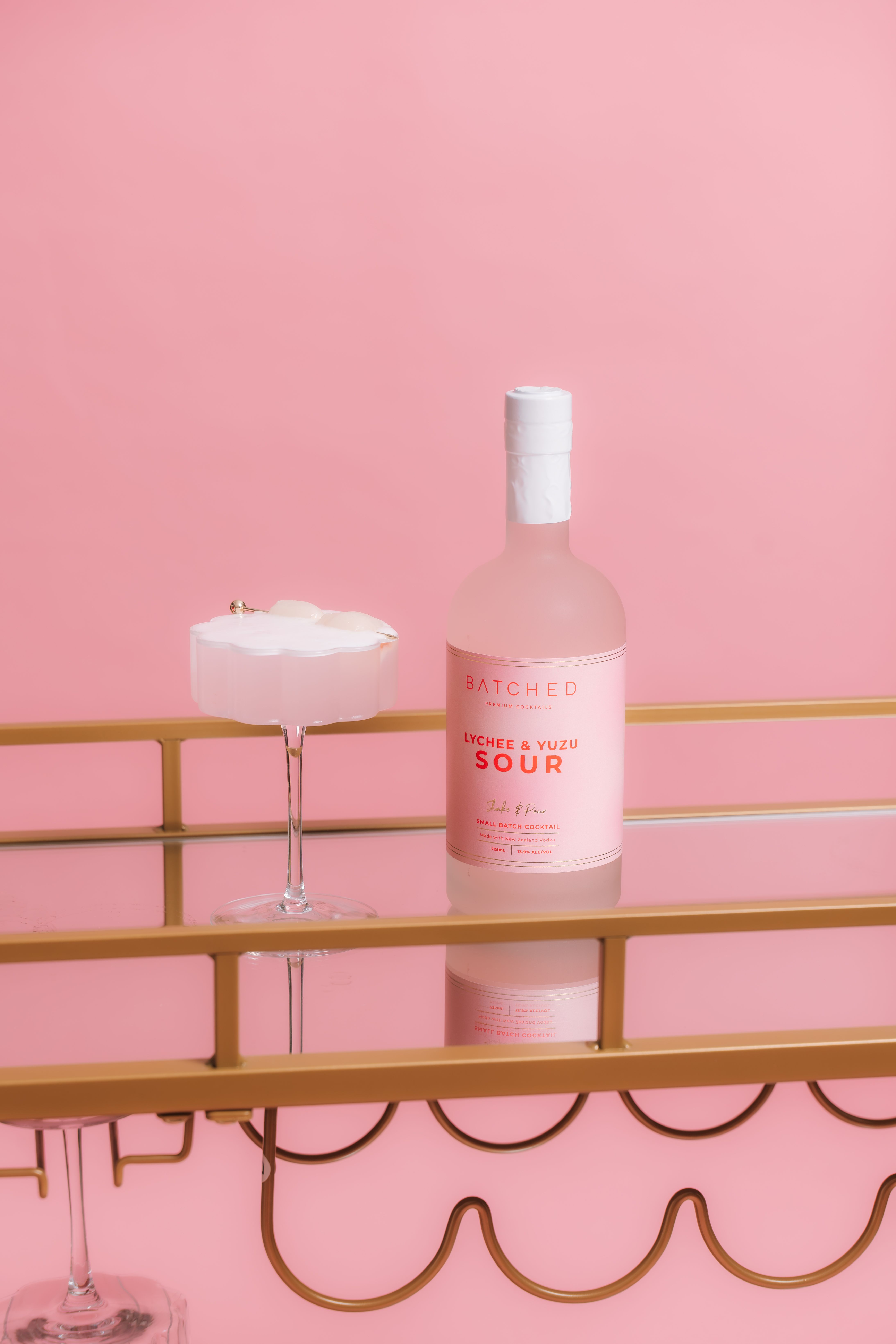 BATCHED Lychee & Yuzu 725mL bottle next to a neatly poured cocktail with Lychees