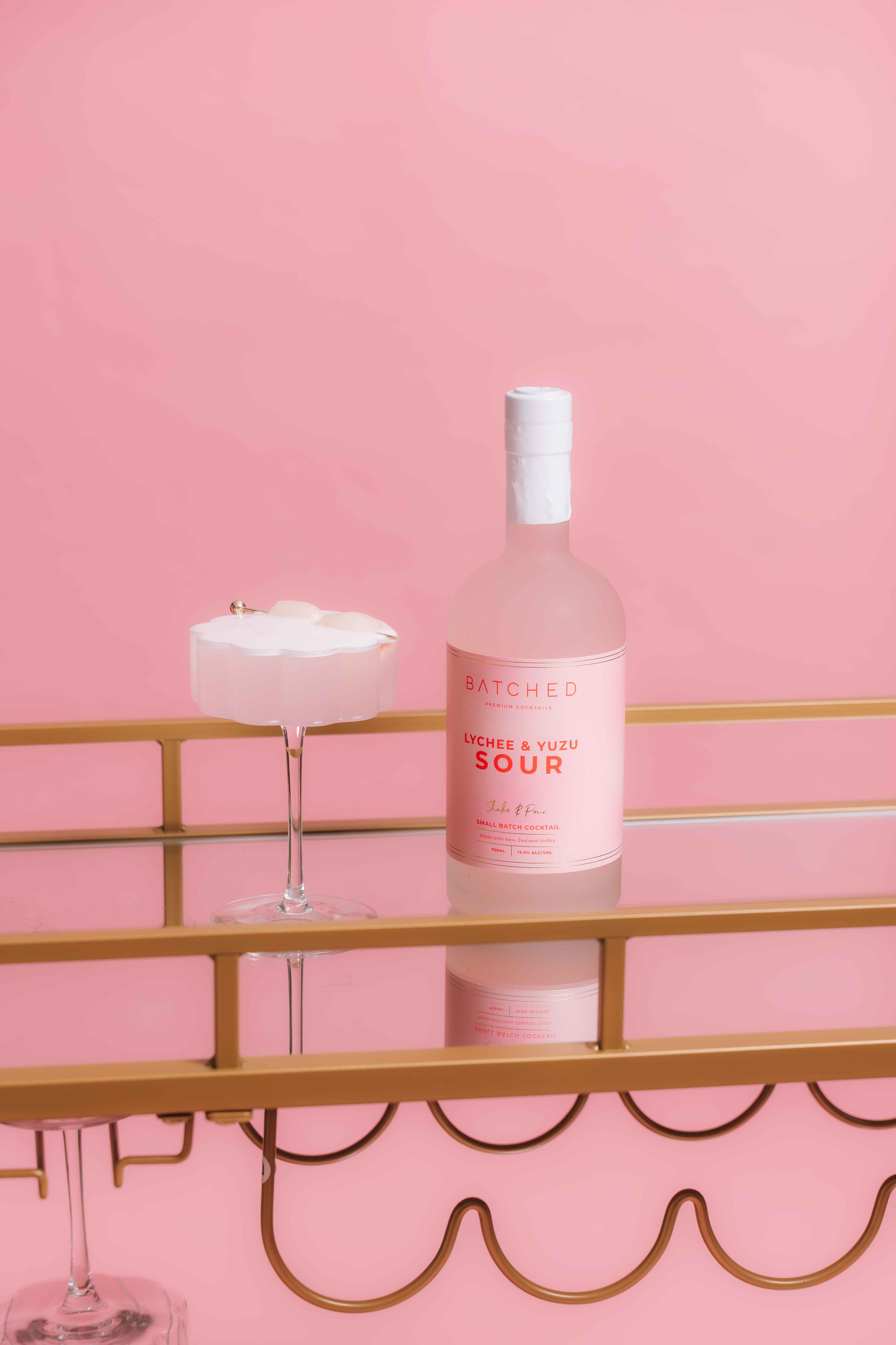 BATCHED Lychee & Yuzu 725mL bottle next to a neatly poured cocktail with Lychees