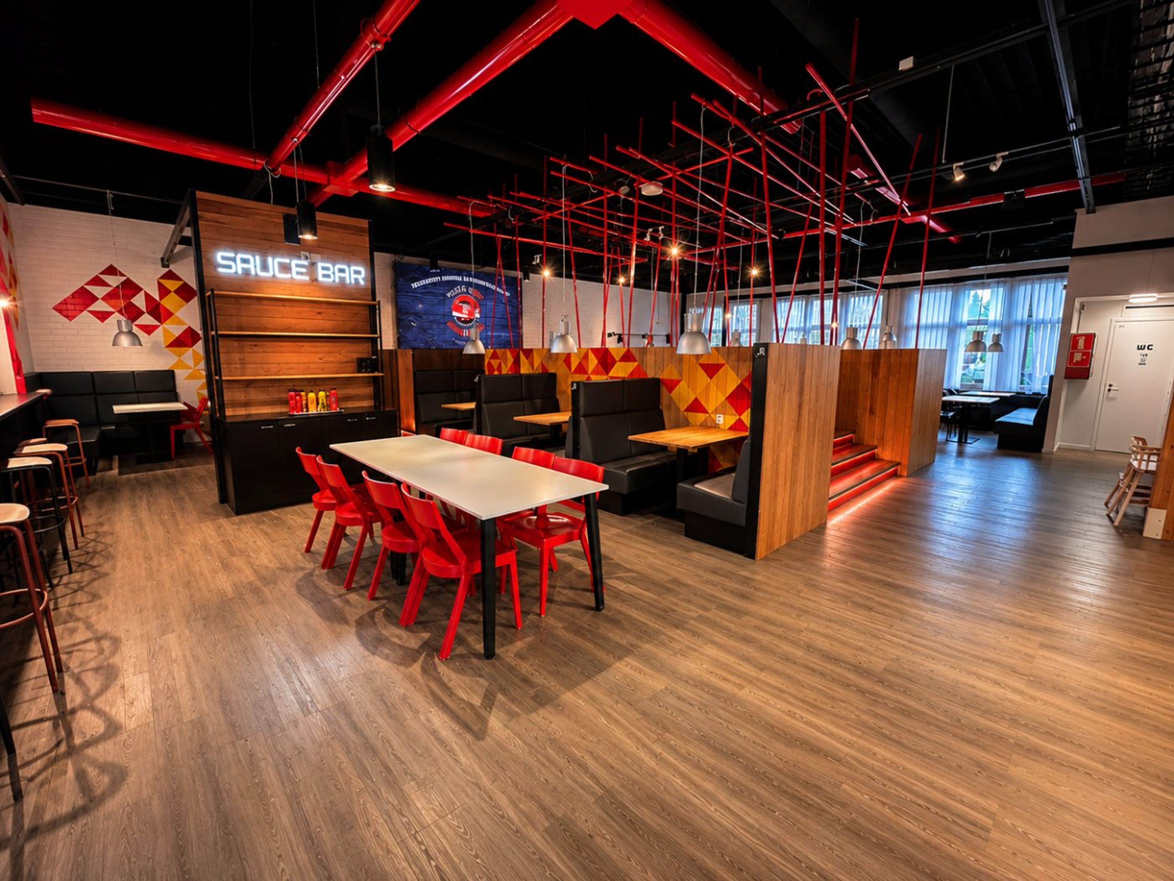 The Piece`n GO dining room: the Sauce Bar neon sign, red chairs and black booths
