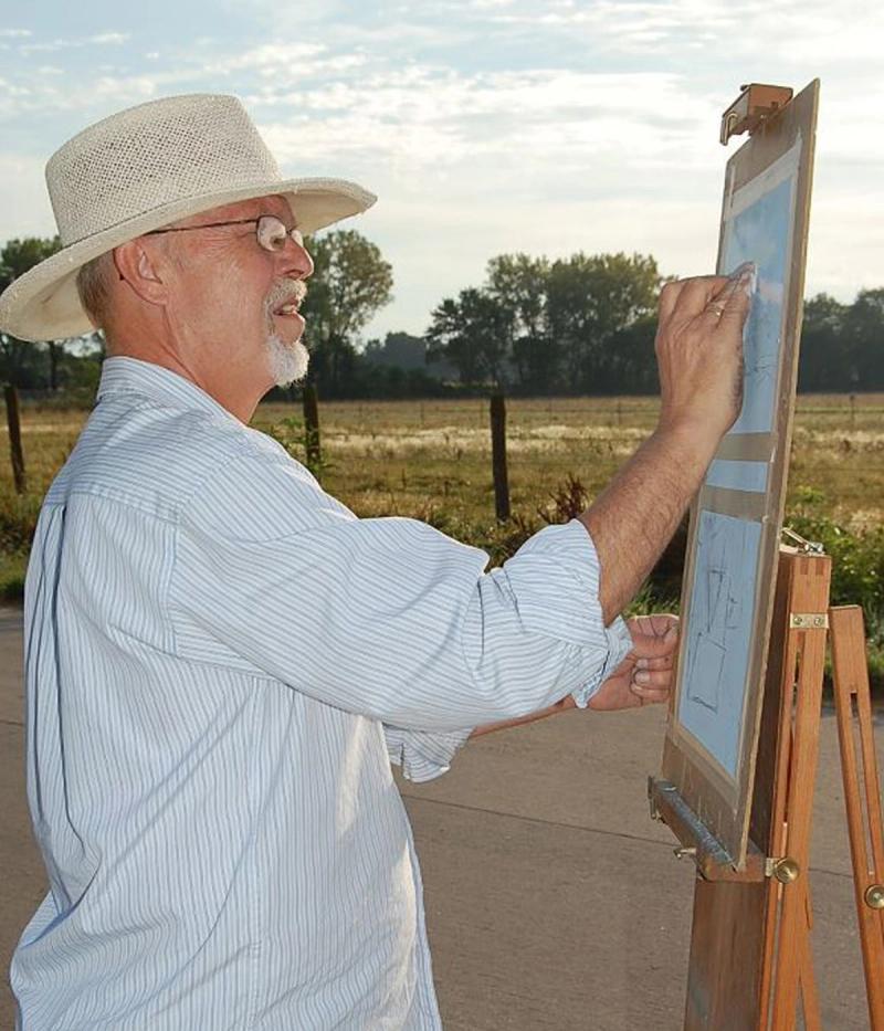 artist painting outdoors at easel wearing white hat