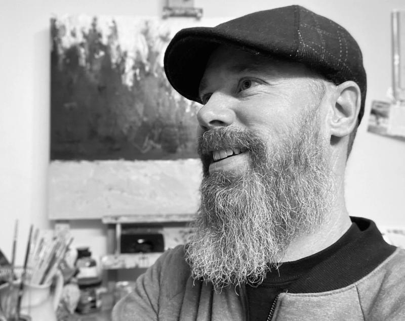 bearded artist smiling in black and white studio portrait