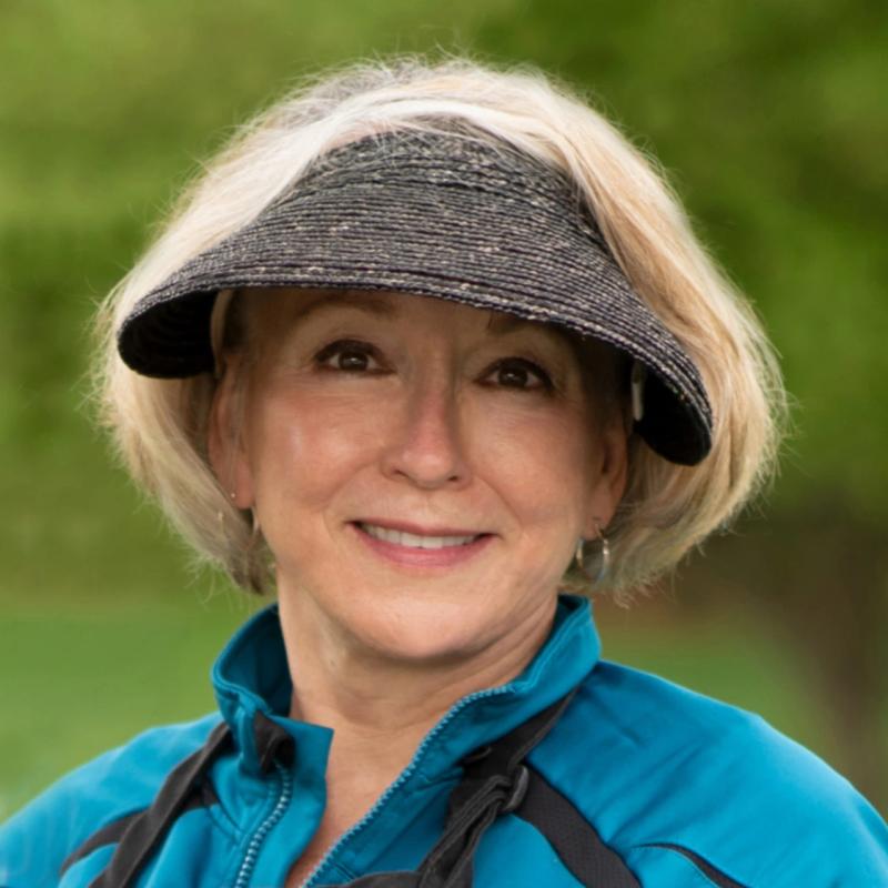 smiling woman in black cap outdoors among trees