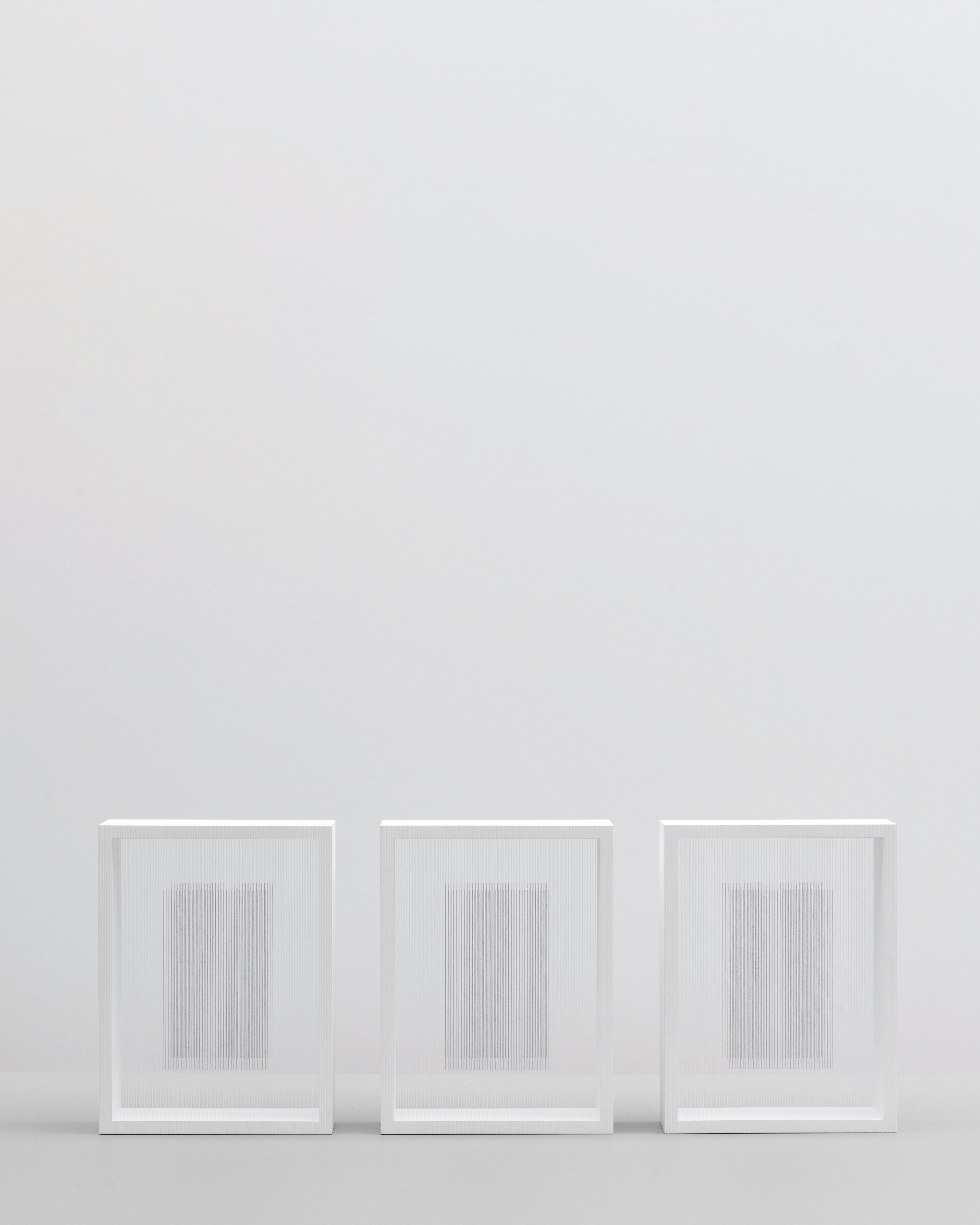 Frontal view of three table-top sculptures (Triptych) by Hadi Tabatabai with string structures held in a frame.