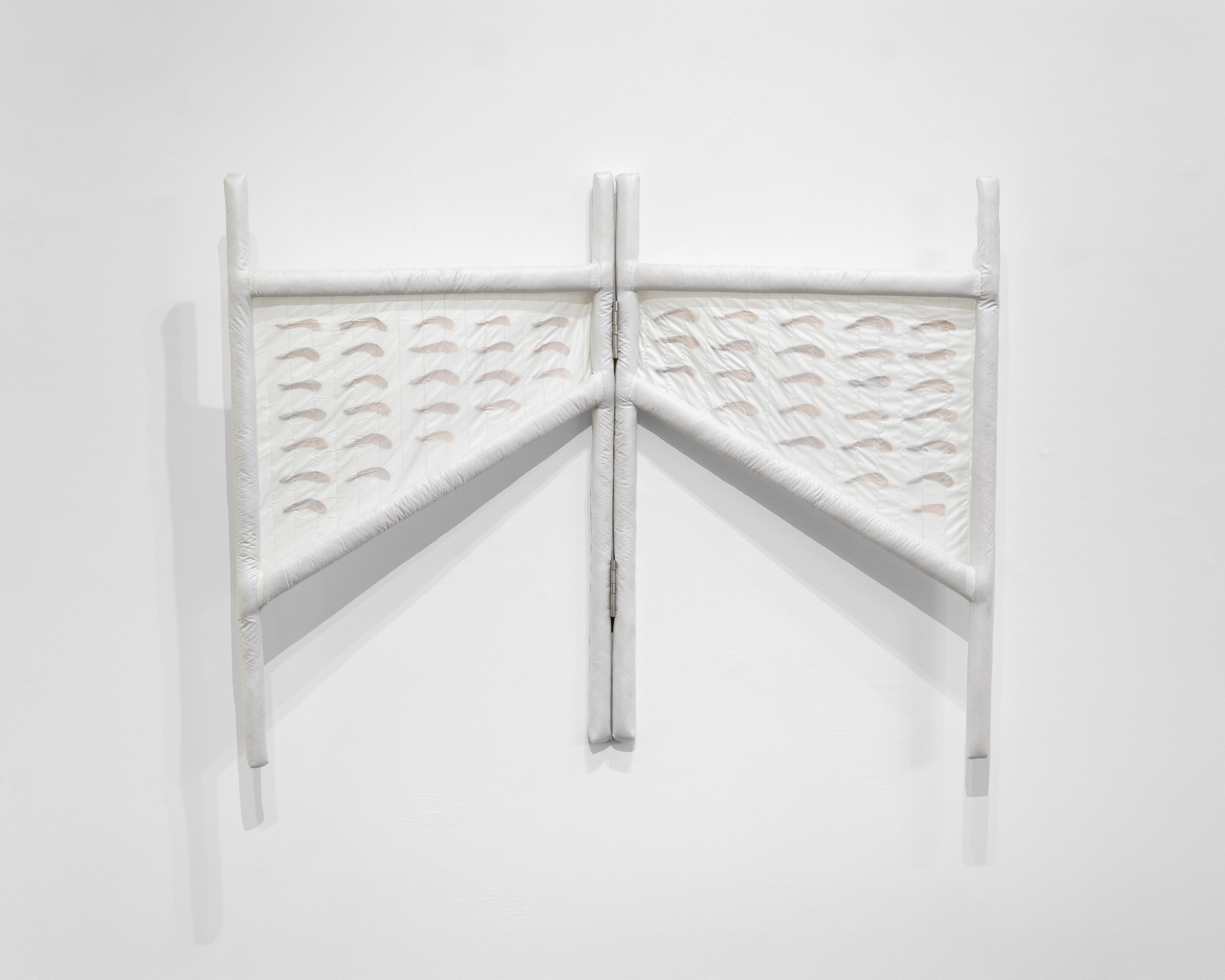 Two white wooden chair backs with textured parachute nylon panels mounted on wall, connected by a central maple seed form creating a symmetrical, sculptural…