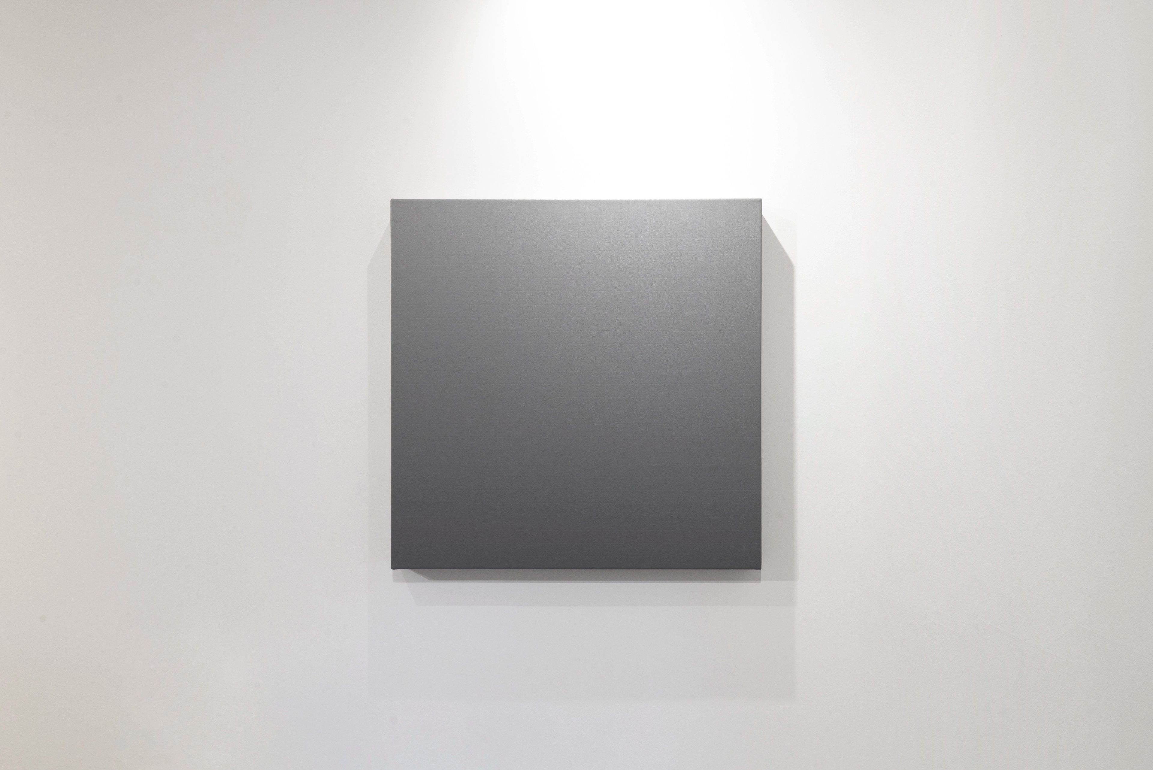 Squarish canvas with gradient from light grey at top to dark charcoal at centre, mounted on white gallery wall casting soft shadow