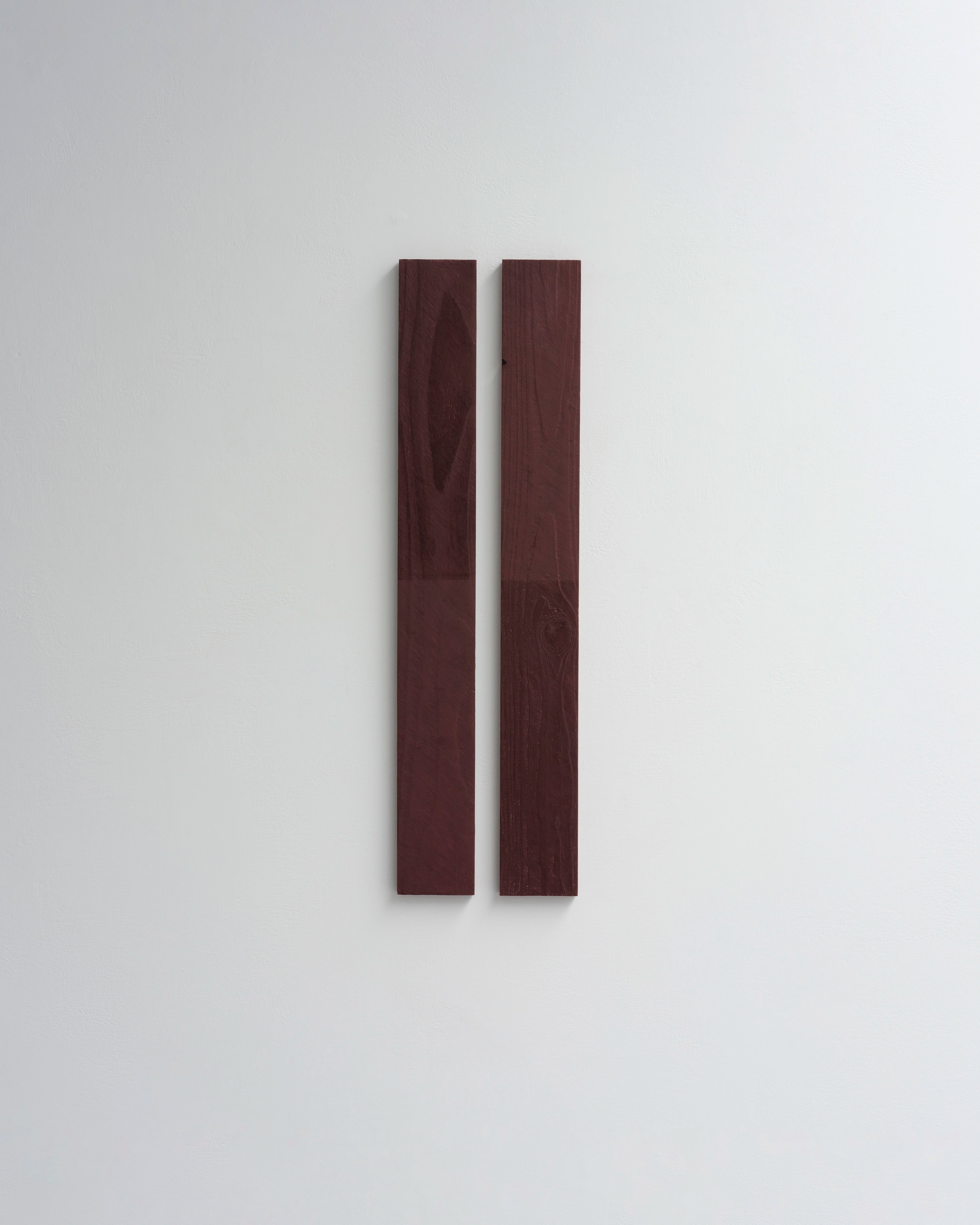 Two tall vertical reclaimed wood panels in deep burgundy, marked with wax pencil, mounted on a white wall
