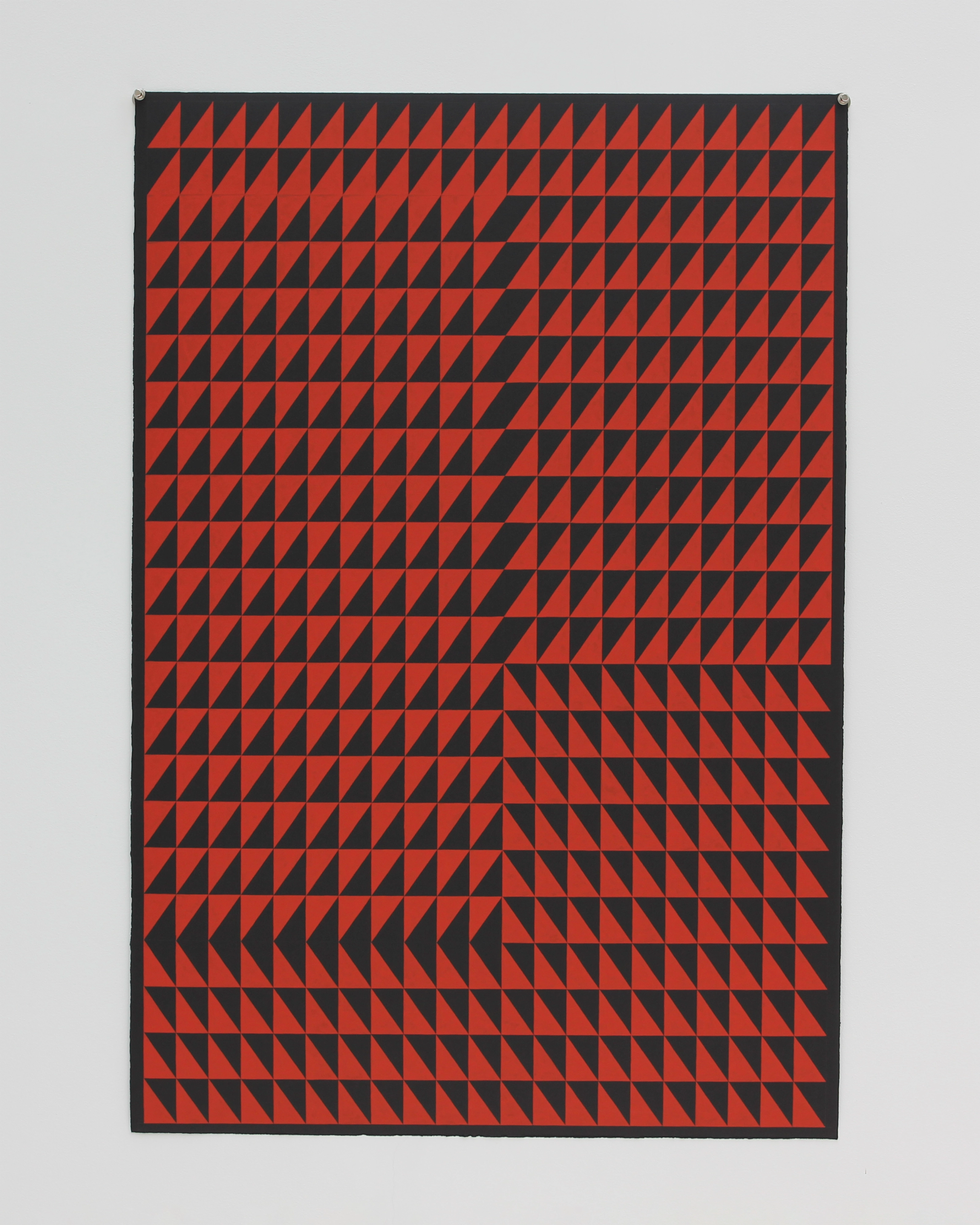 Geometric composition of red and black triangular shapes arranged in a grid pattern, creating optical movement across a dark paper surface