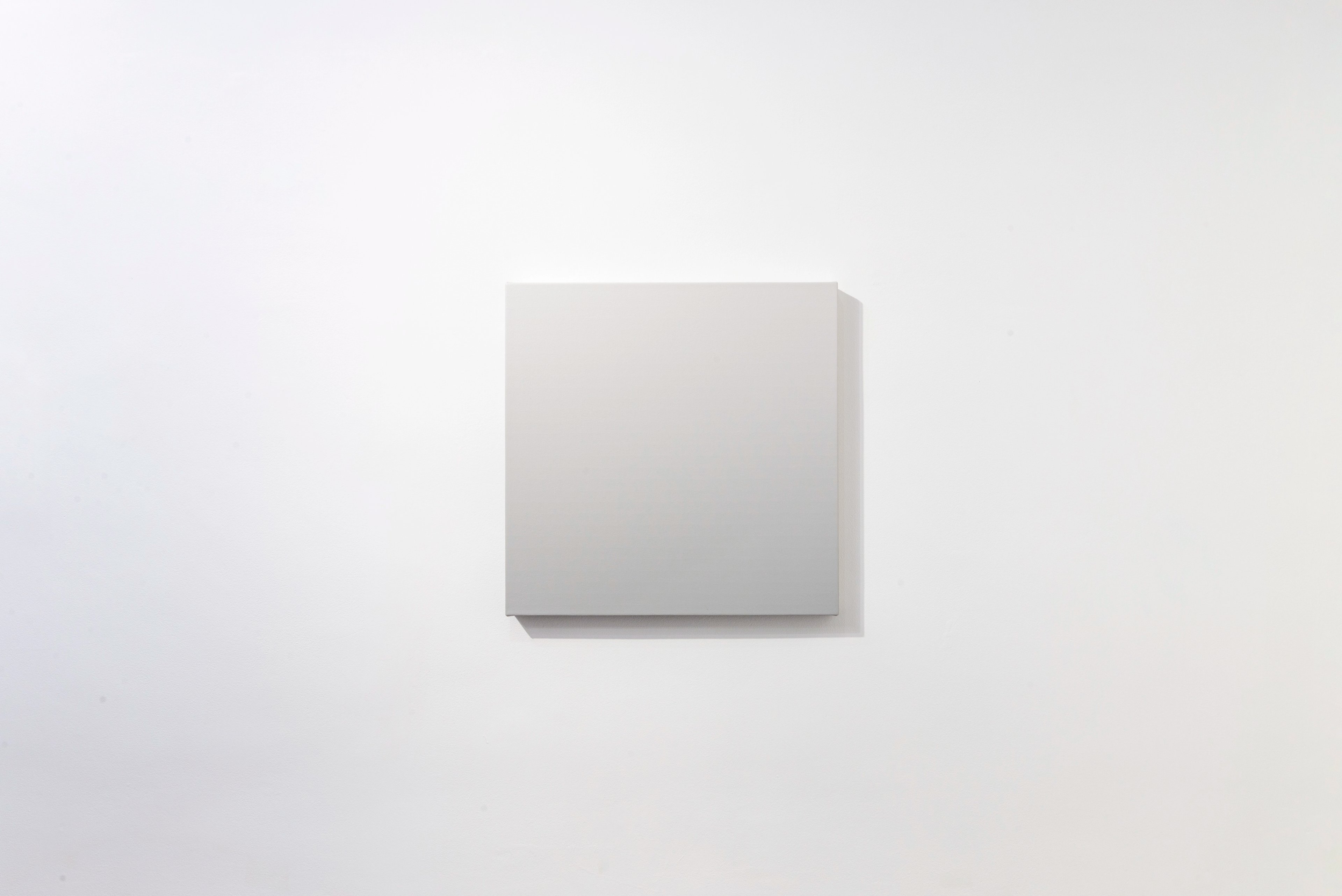 Square acrylic canvas with subtle grey gradient from light top to darker bottom, casting soft shadow on pale wall
