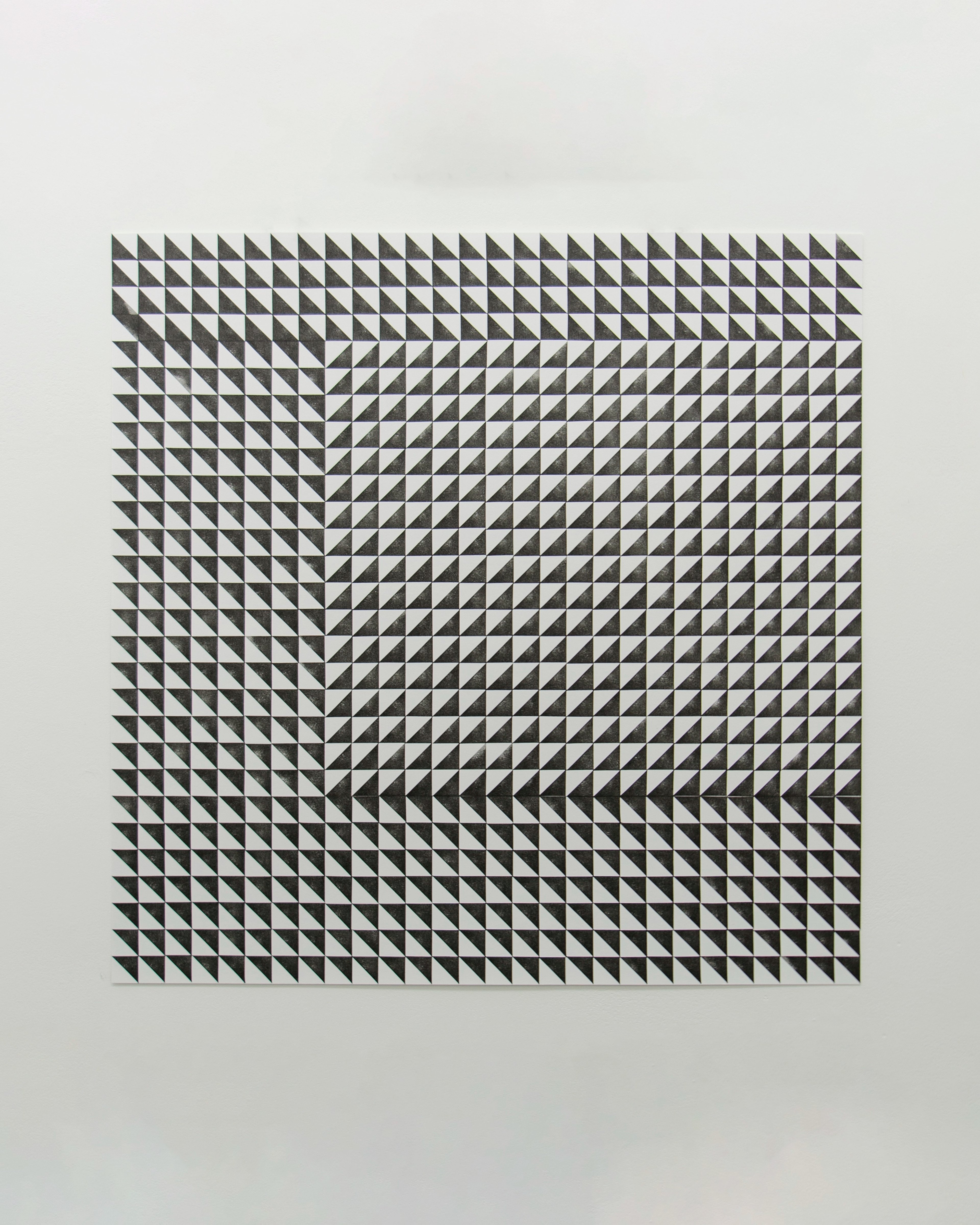 Geometric pattern of thousands of small black triangles arranged in a grid on white paper, creating an optical illusion of depth and directional movement acr…
