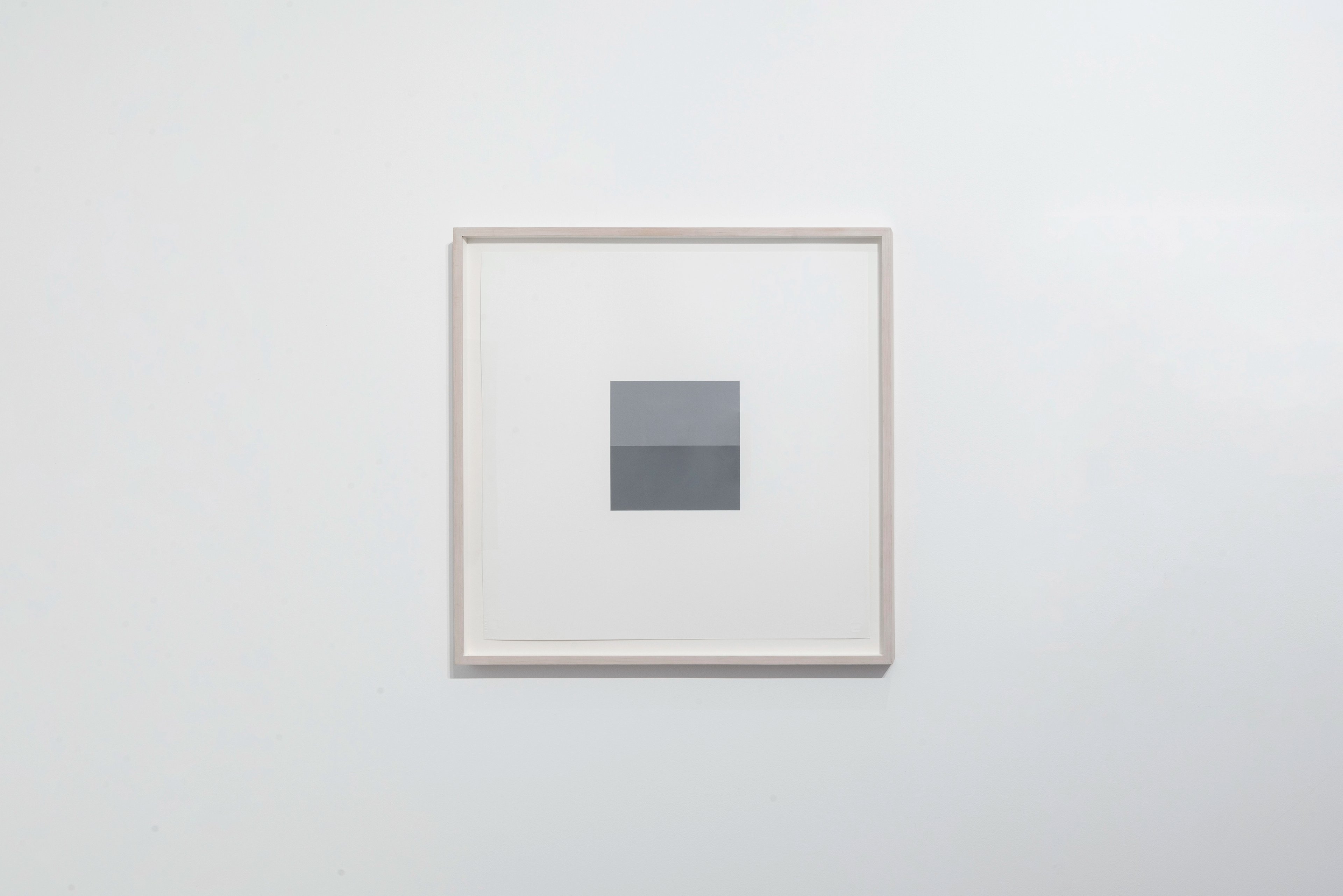 Framed acrylic on paper depicting two stacked grey rectangles of slightly different tones on off-white ground, centered within beige frame