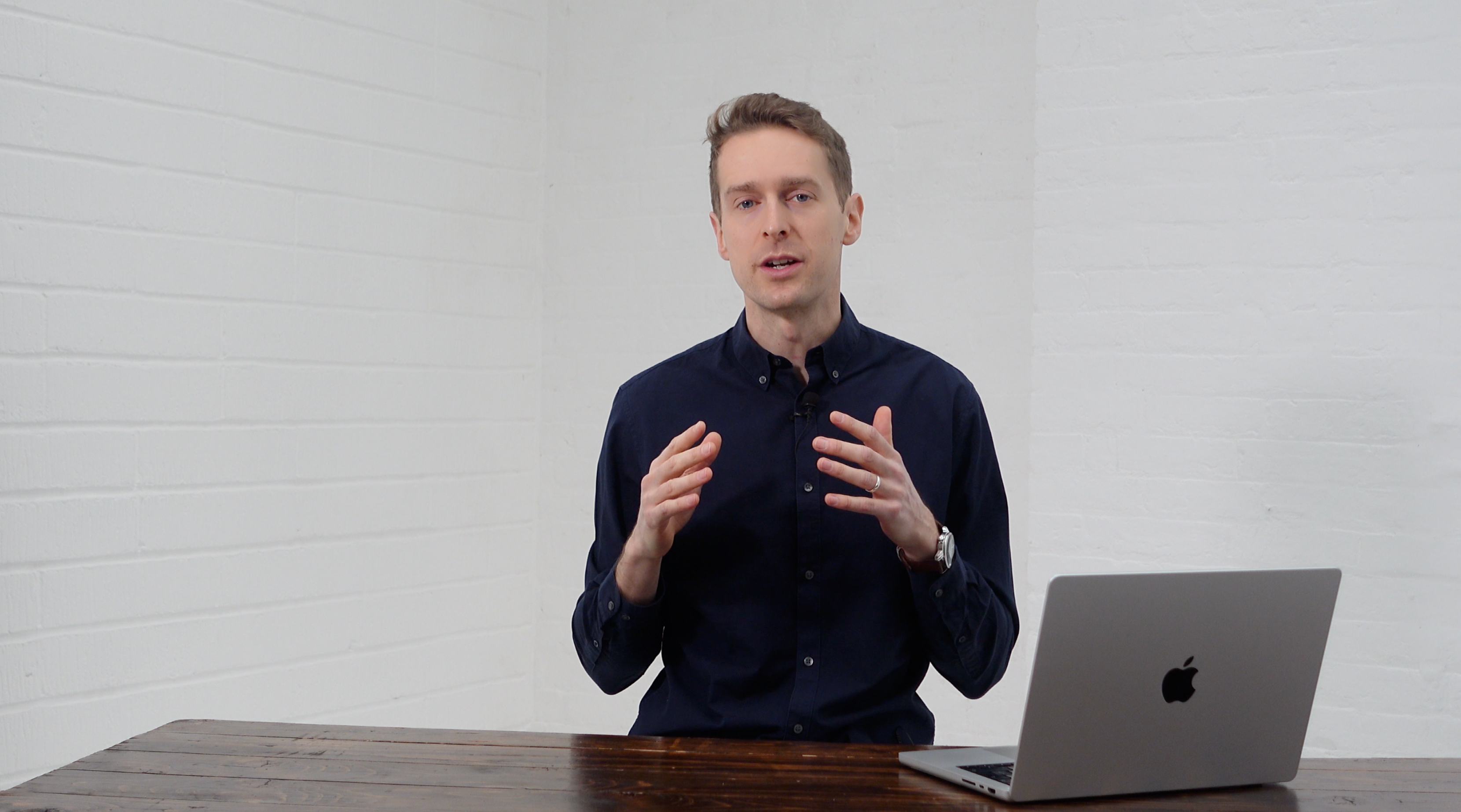 Co-founder James Kuht, MBE and CEO of PAIR delivering an on-camera presentation at Brixton Warehouse, standing behind a table with a laptop in a bright white studio space.