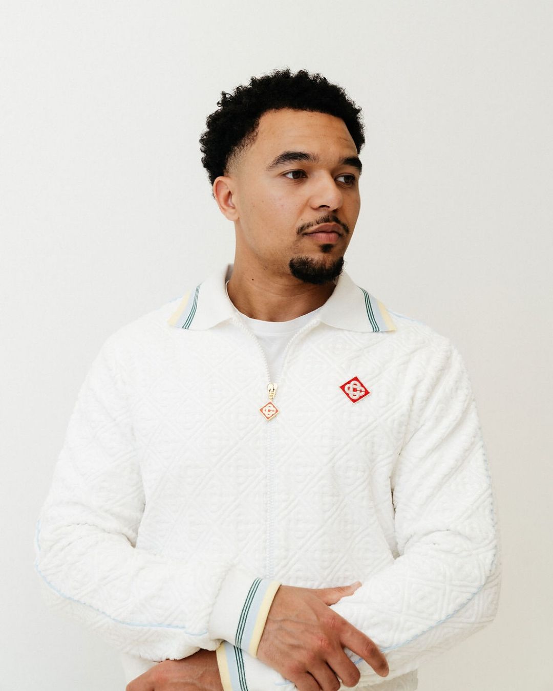 Artist Jacob Arli seated in front of white backdrop wearing Casablanca top.