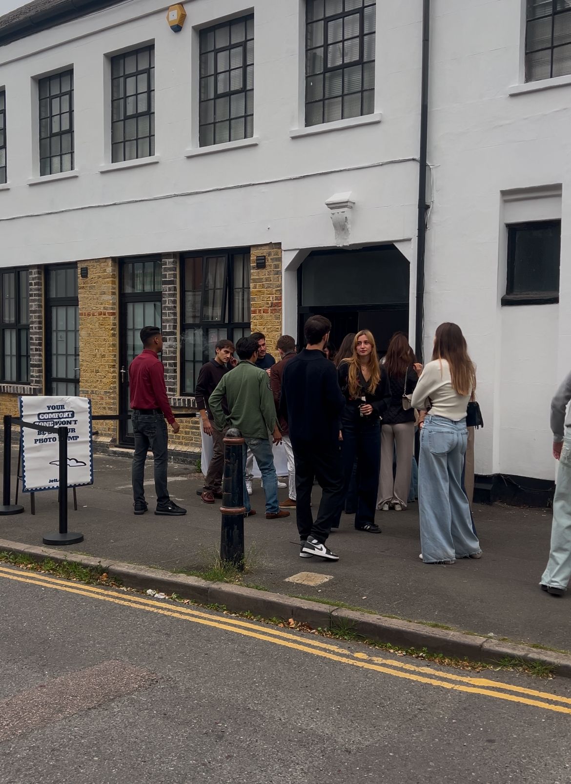 Guests gather and chat outside Brixton Warehouse before the JETLOST Sunday Family Reunion event, with a branded sign welcoming attendees to the venue.