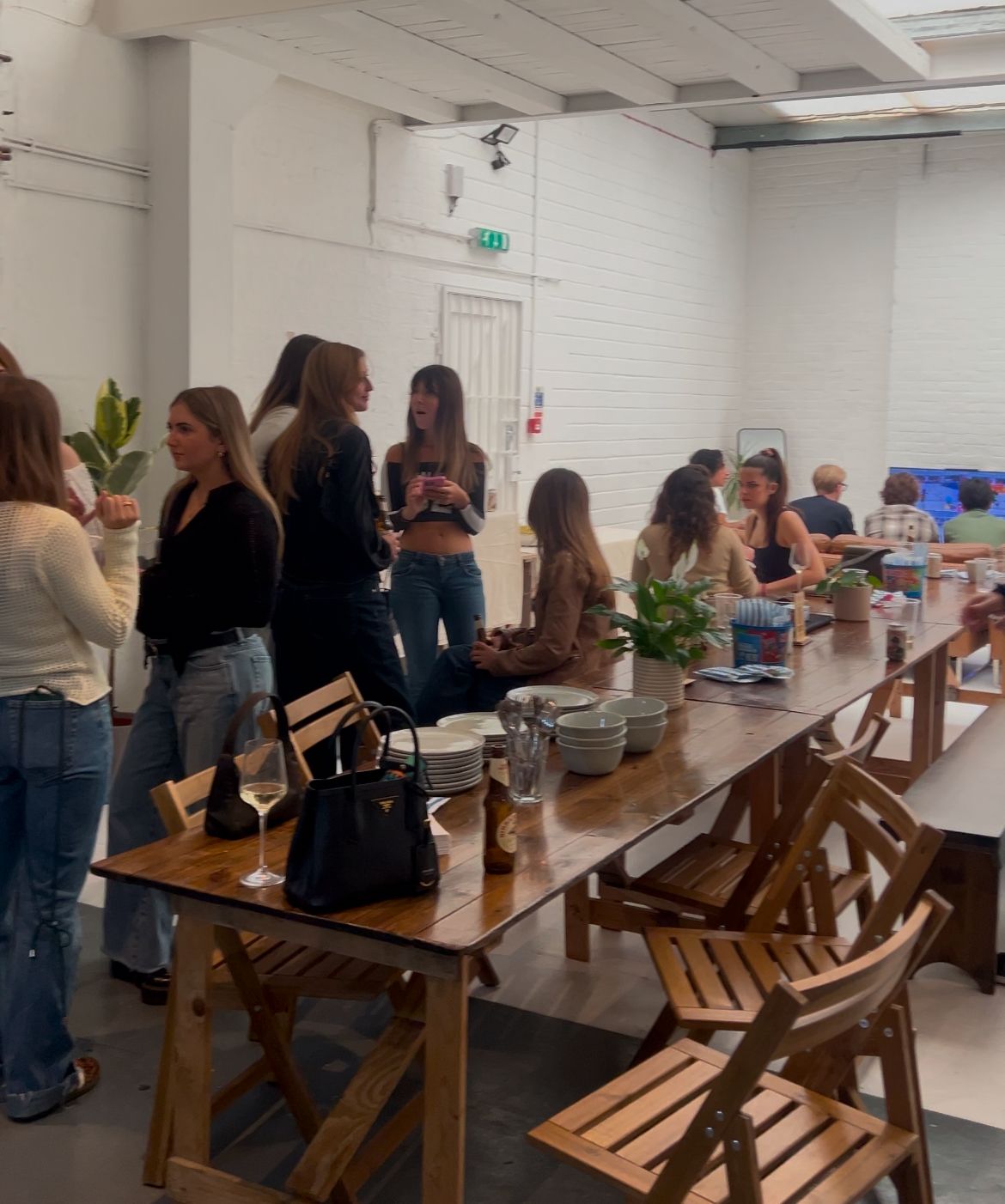 Guests chatting and relaxing around a long wooden dining table during the JETLOST Sunday Family Reunion event at Brixton Warehouse, surrounded by drinks, plants, and a laid-back community vibe.