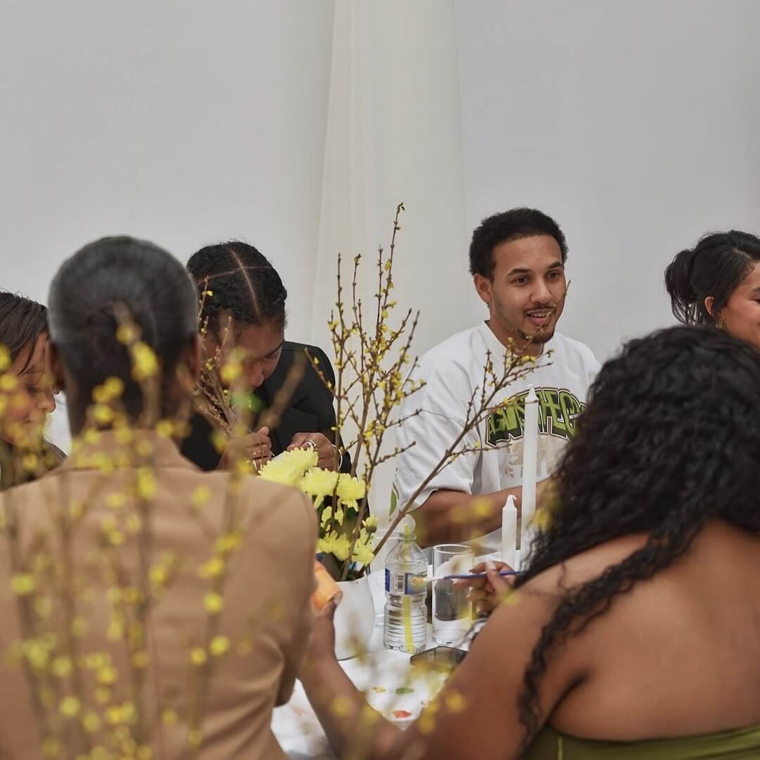 “Guests gathered around a themed communal dining table decorated with yellow flowers at Brixton Warehouse.”