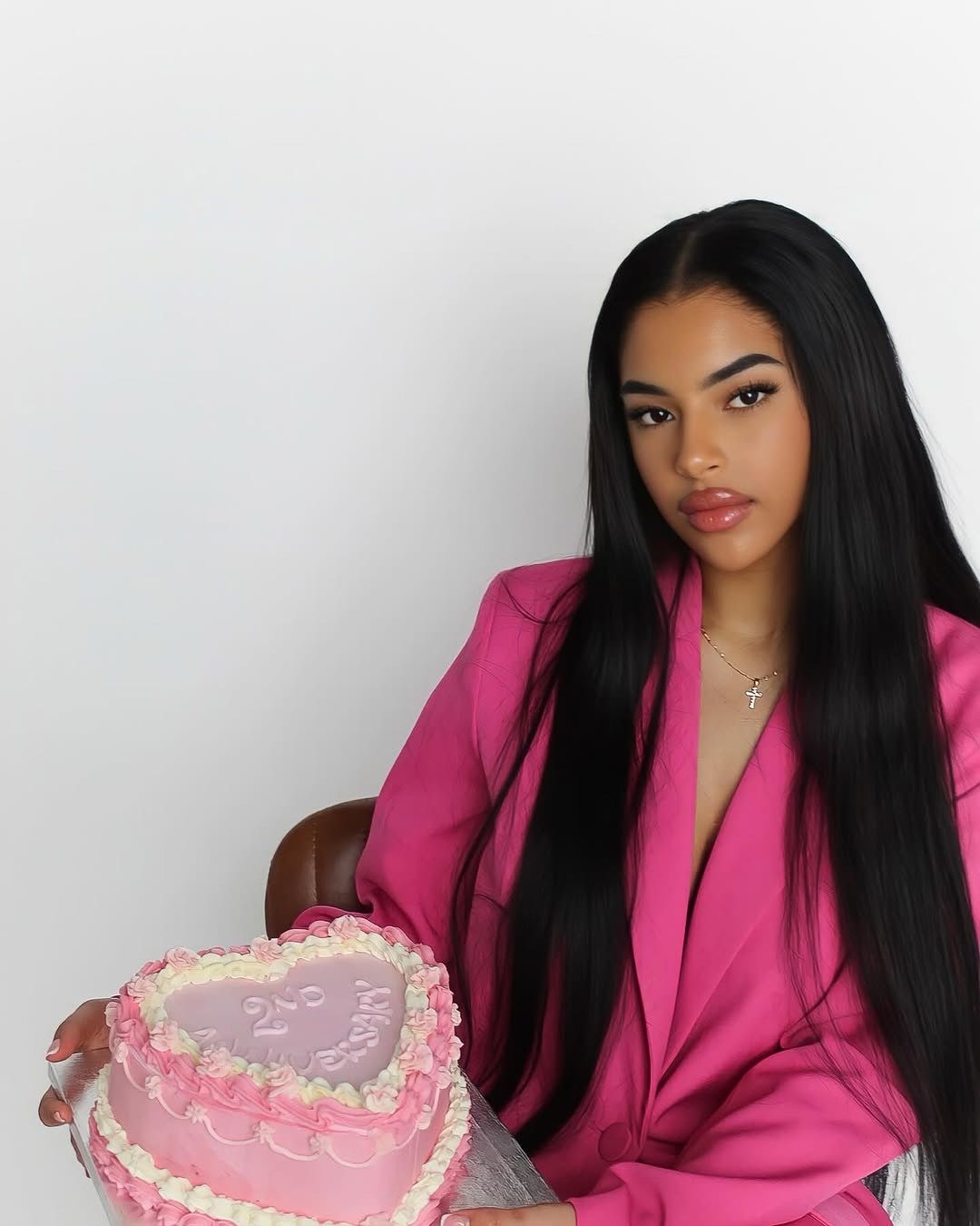 Female founder celebrating a business milestone with a branded anniversary cake during a studio photoshoot at Brixton Warehouse.
