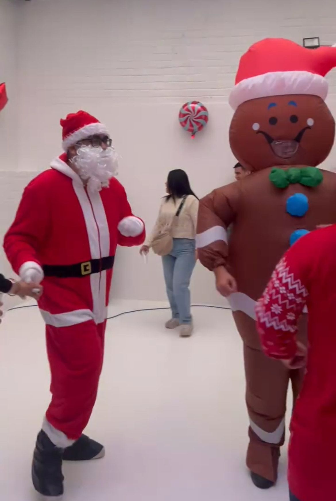 Father Christmas and inflatable elf ready for kids’ Christmas party in white warehouse venue.
