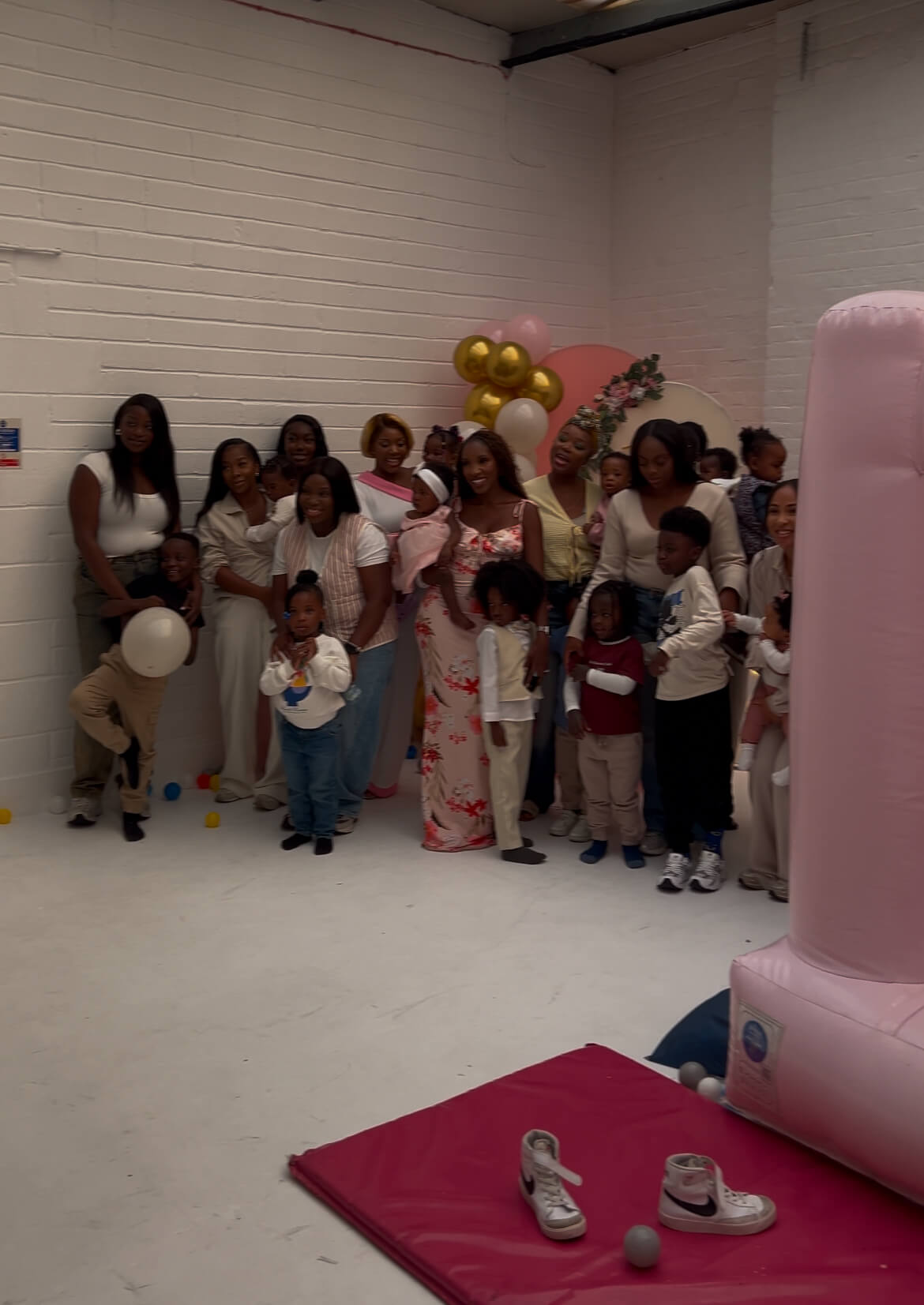 “Large family group gathered at Brixton Warehouse for a celebration, with children and balloons in a bright studio space.”