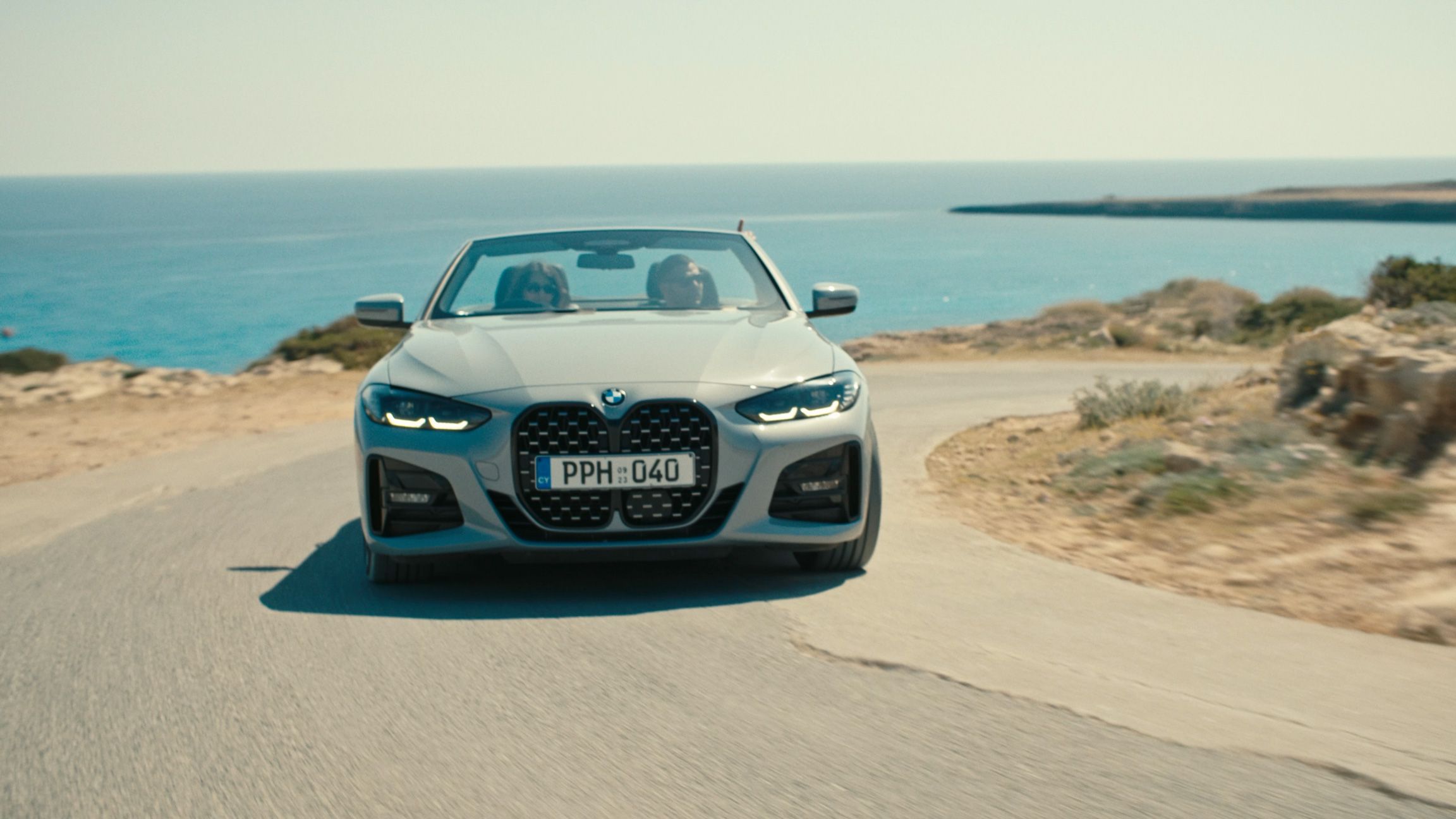 Convertible approaching on a coastal road with the Mediterranean Sea behind it