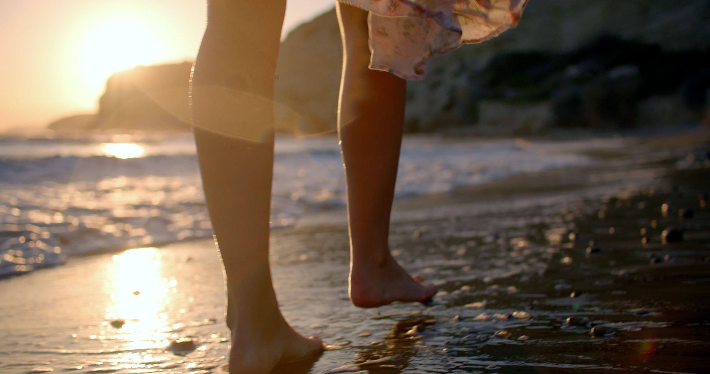 Bare feet stepping into the sea at sunset