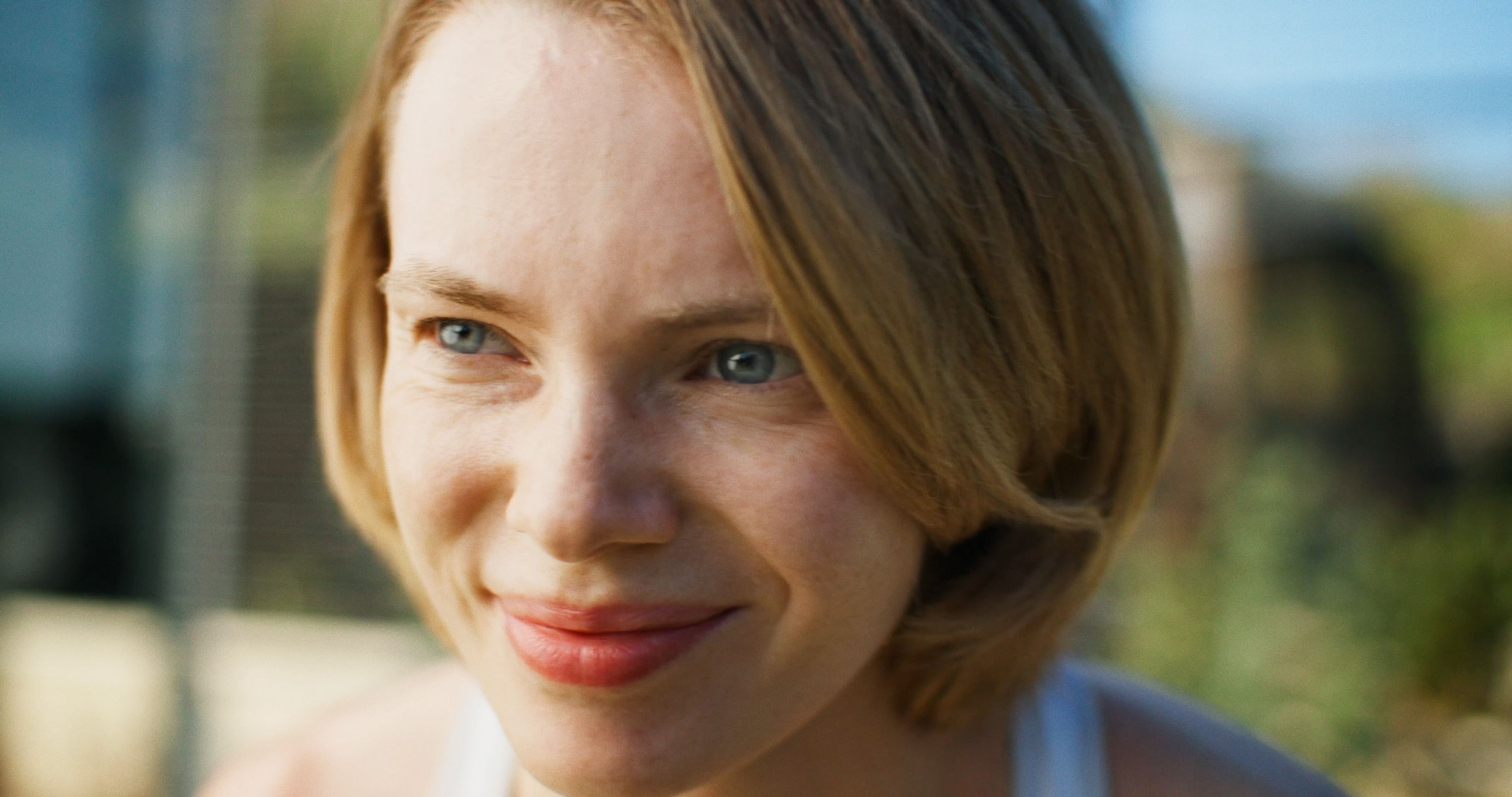 Close-up portrait of a smiling young woman outdoors in natural light.