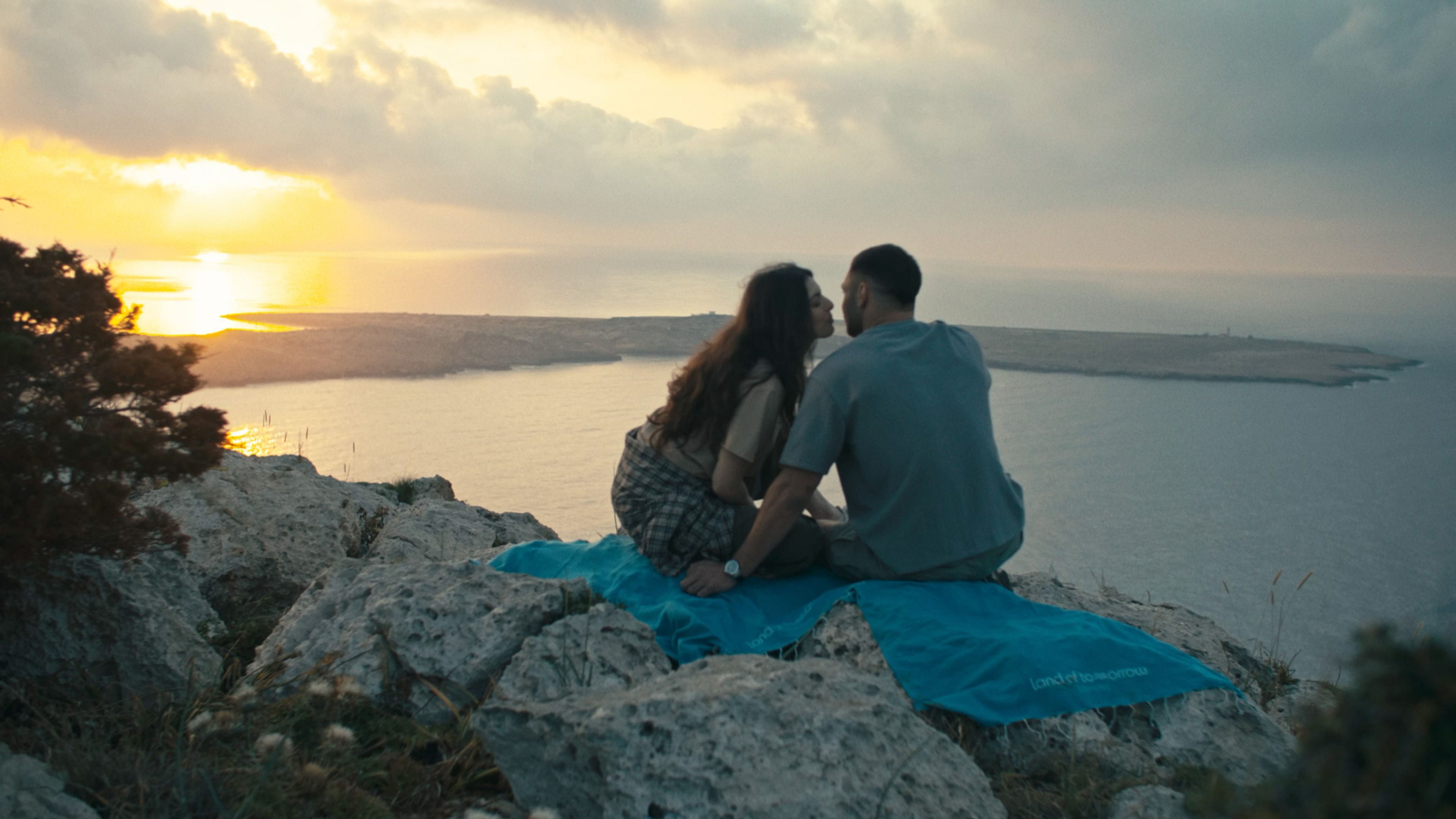Young couple sharing a sunset picnic on a rocky coast in Protaras